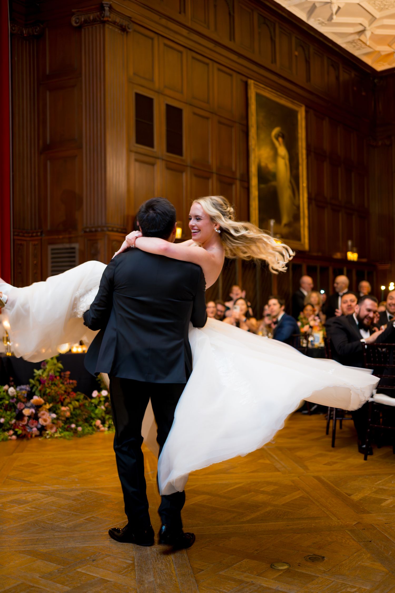 A couple performs an elegant dance dip during their wedding reception in a grand ballroom.