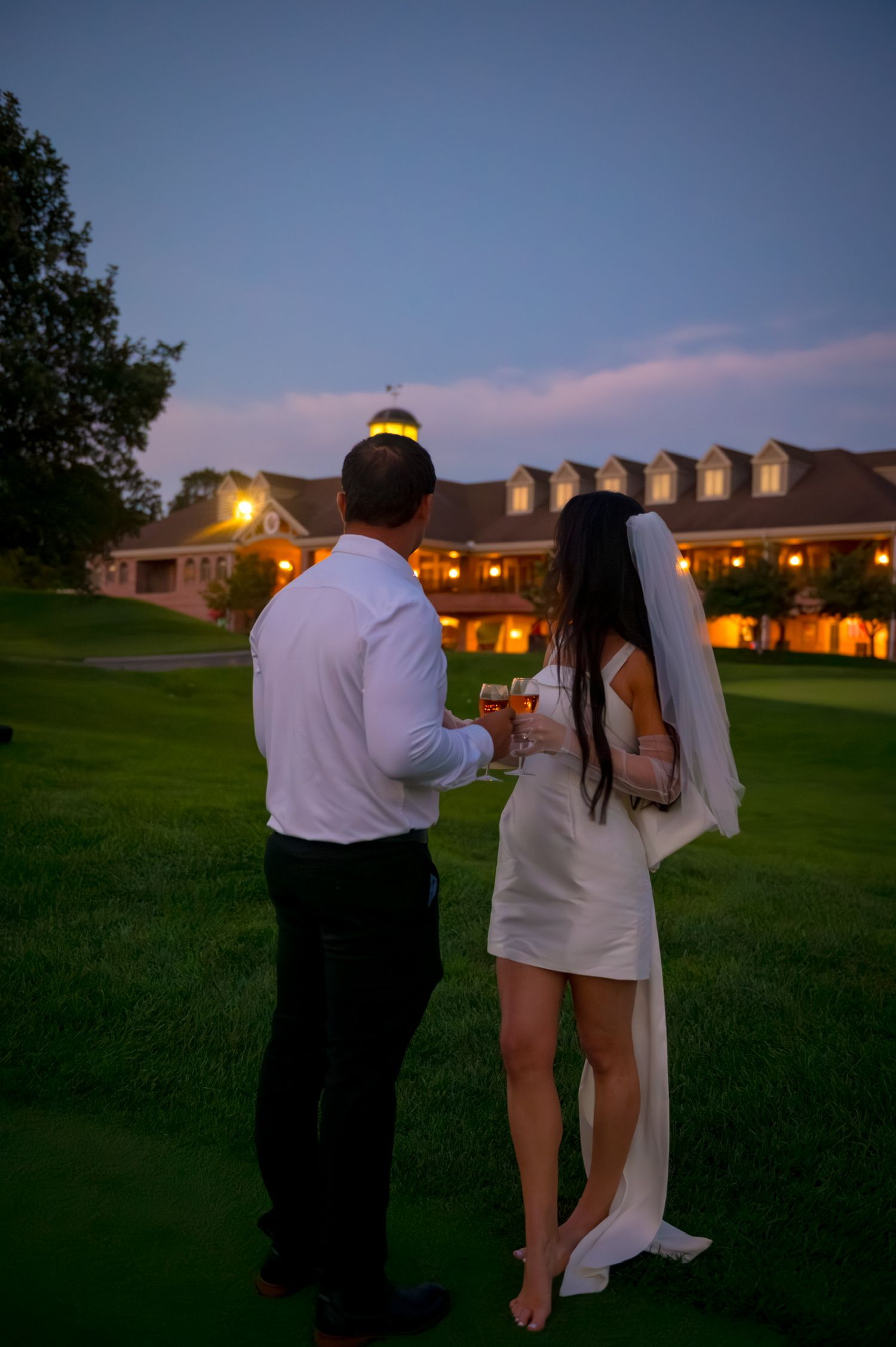 Evening scene at a golf club with lit buildings in the background.