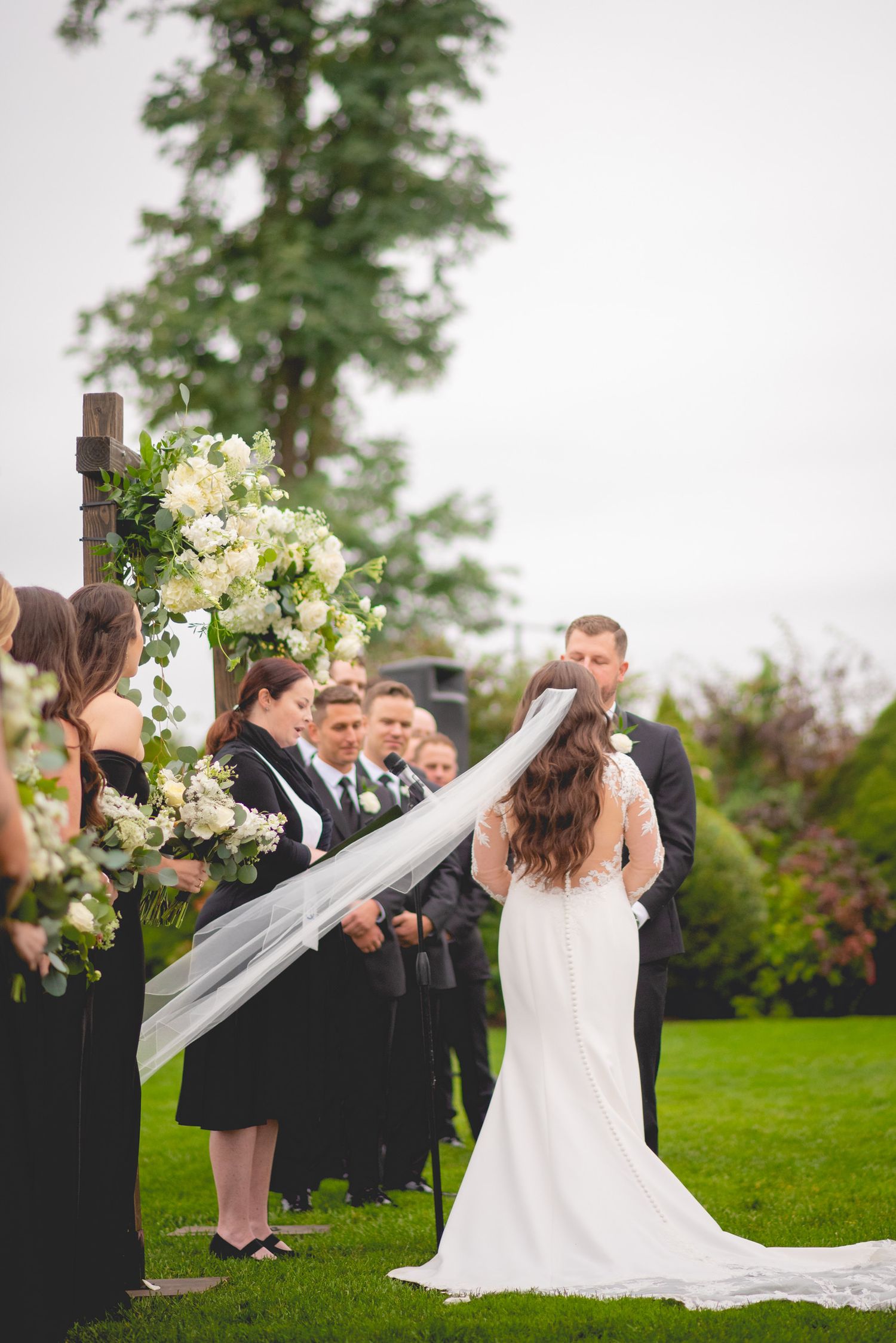 Wedding celebration on a lush green lawn with formal attire and floral arrangements.
