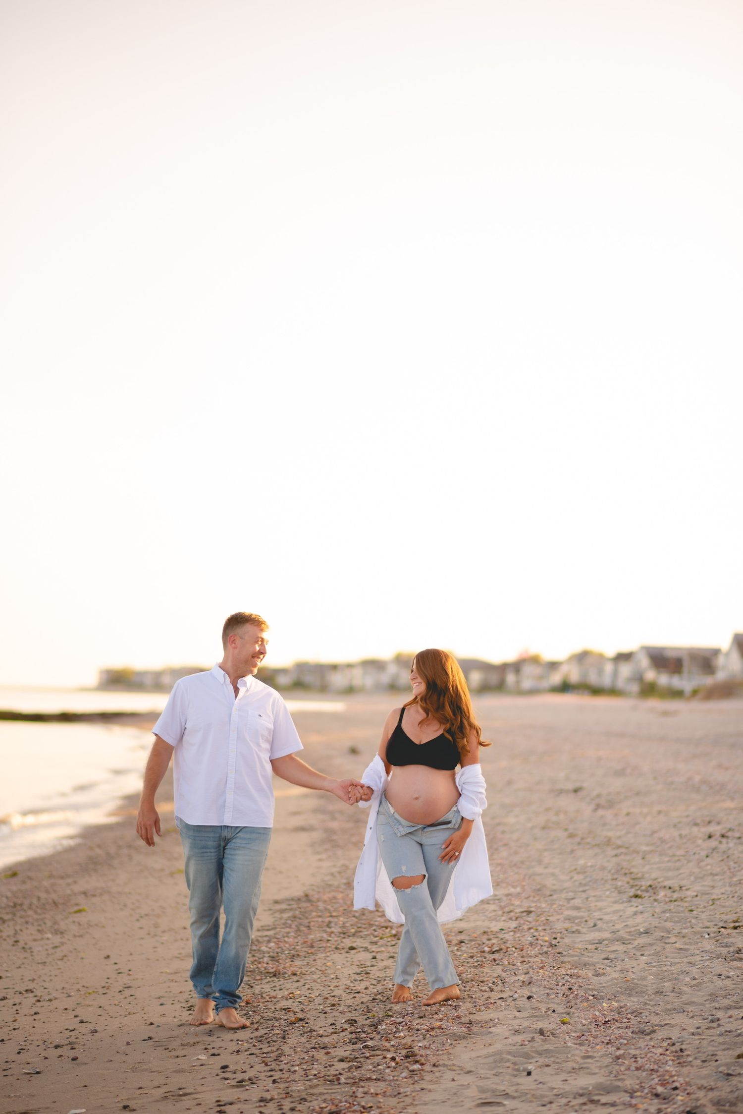 A couple walking and playing on a sandy beach at sunset.