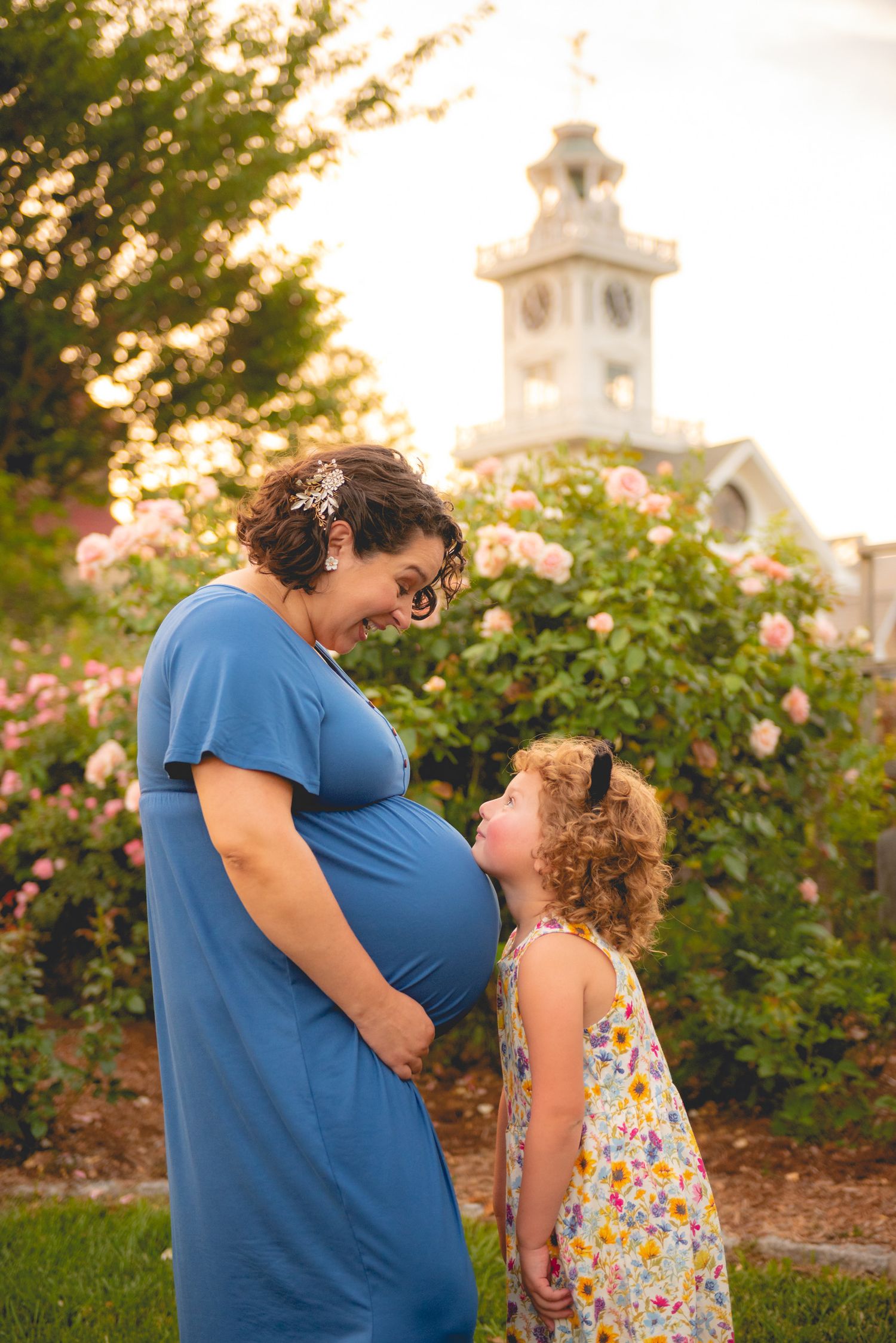 A tender moment between parent and child in a garden with blooming roses at sunset.