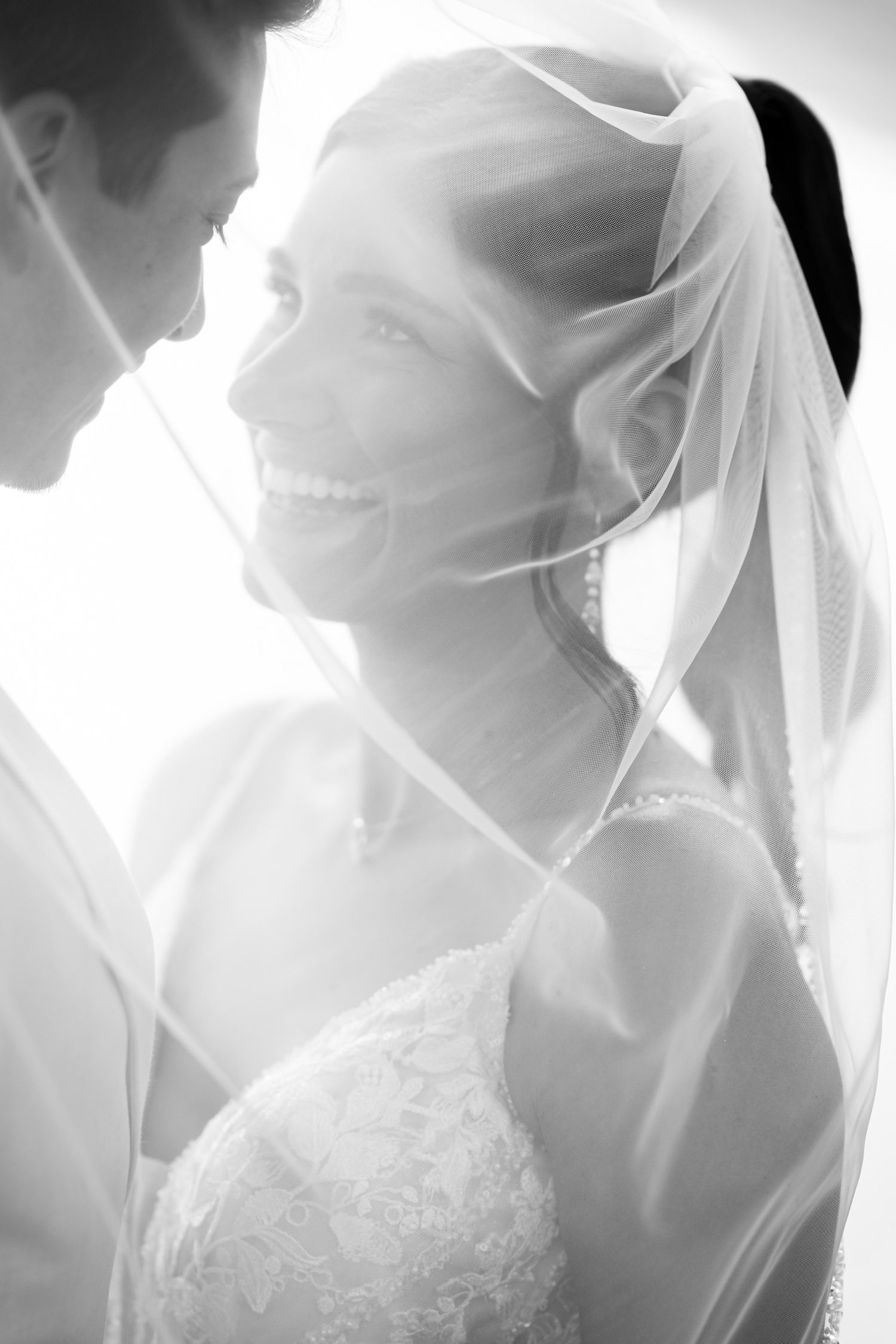 Ethereal black and white close-up of bride's veil with soft lighting creating dreamy effect.