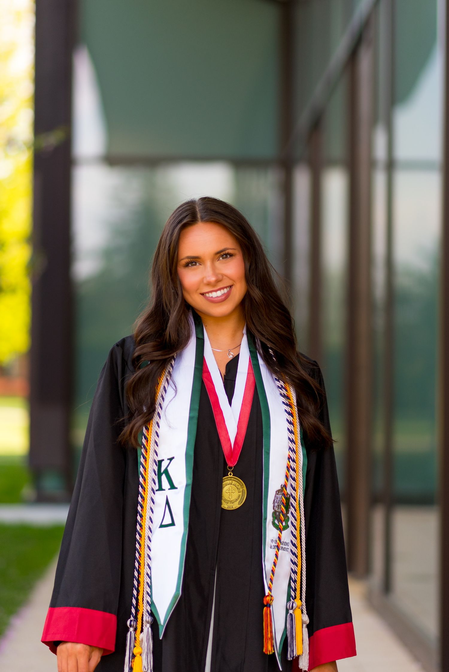 Sacred Heart University graduate wearing black gown with colorful stoles and medals celebrate their academic achievements.
