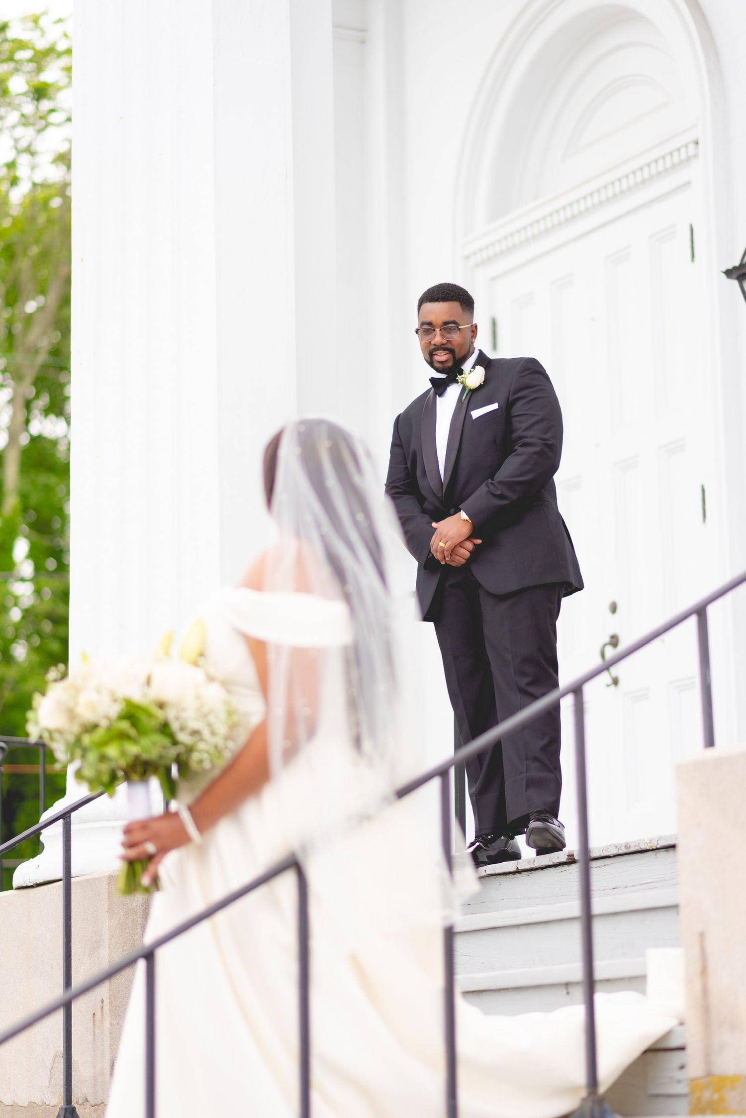 Wedding moment captured at white columned entrance with elegant architecture.