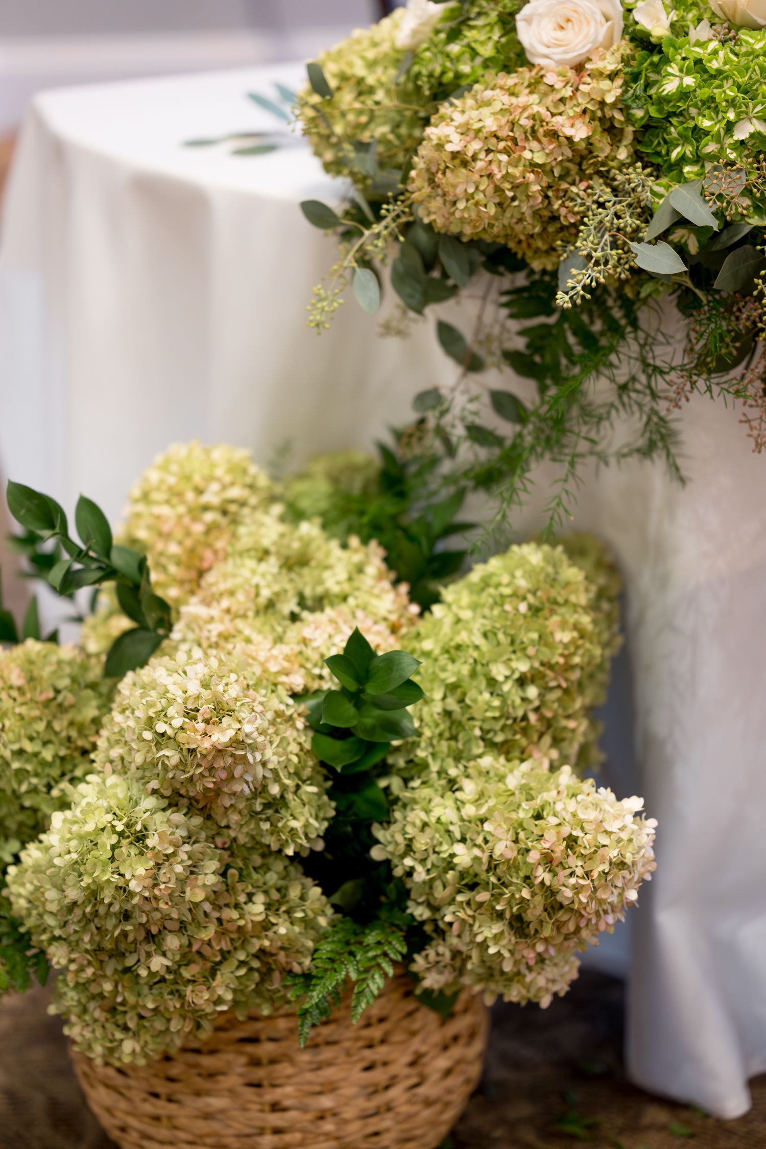 Rustic basket arrangement filled with fresh cream hydrangeas and greenery.