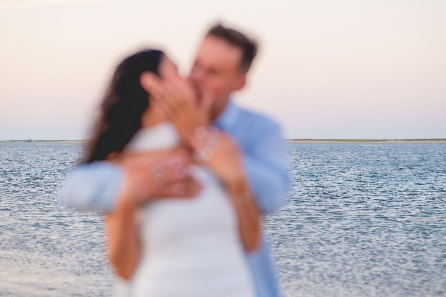 Romantic beach photoshoot captures couple's loving moments by the water at Chatham Lighthouse Beach in Chatham, Massachusetts.