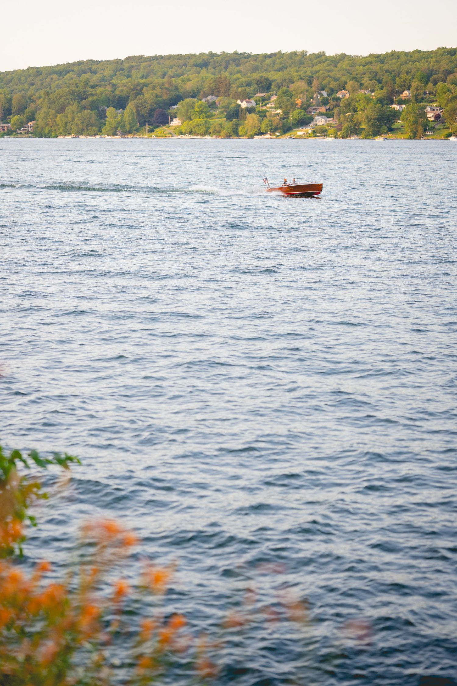 Scenic Candlewood Lake view with a small red boat and autumn foliage in the foreground.