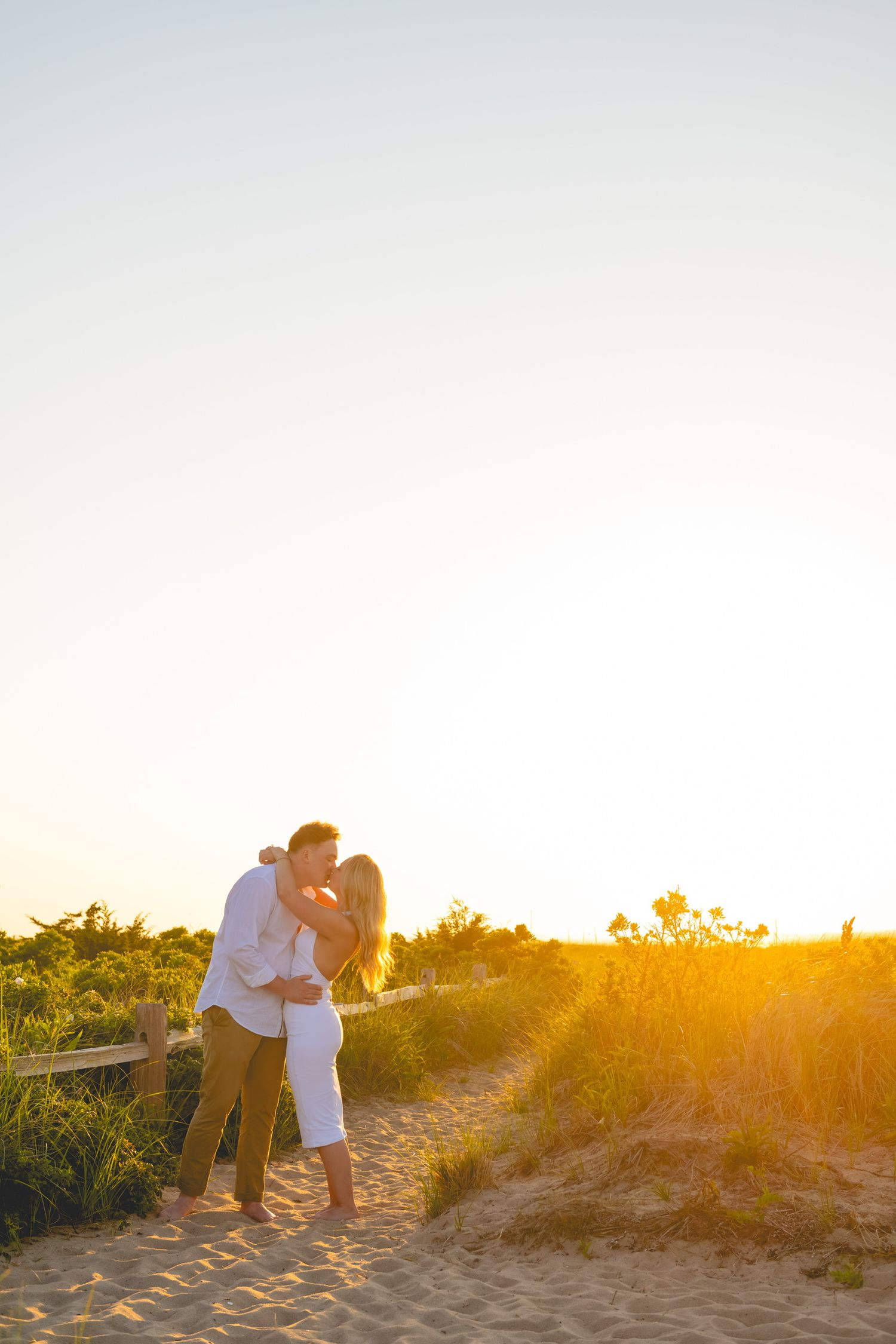 A romantic moment captured in golden sunlight on sandy beach path in Watch Hill, Rhode Island.