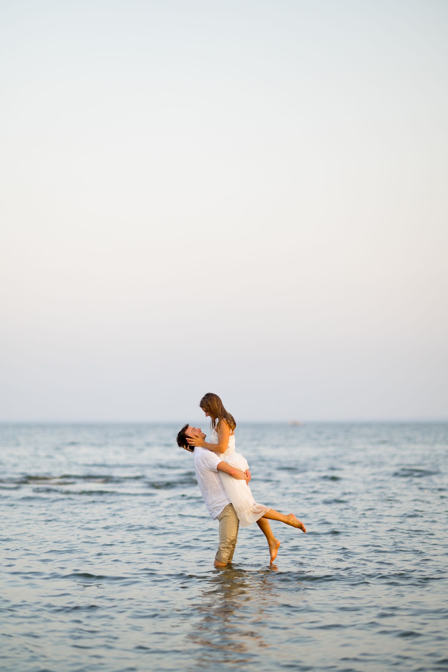 Couple dancing and embracing in shallow ocean waters during a romantic seaside photoshoot.