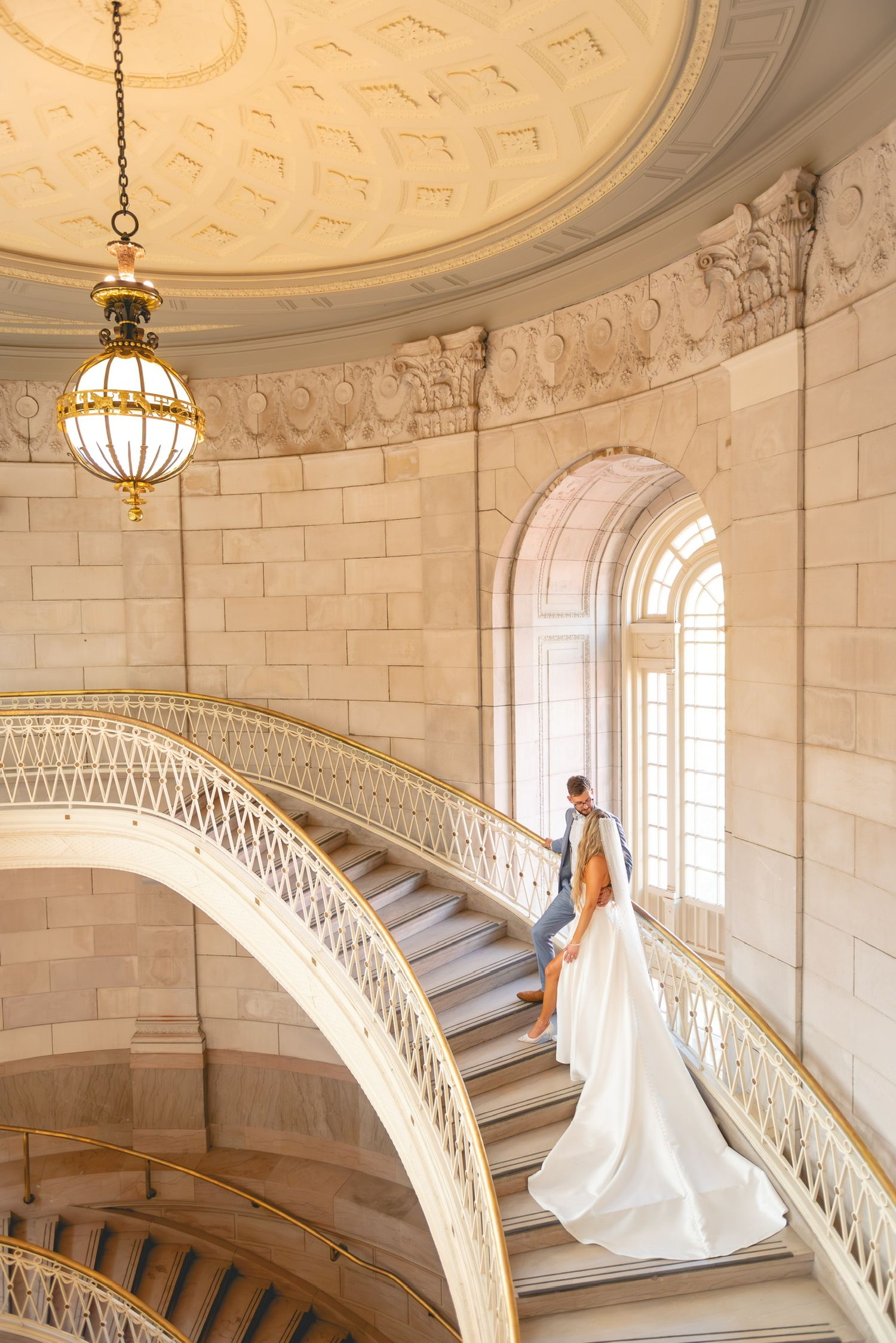 Grand staircase with ornate architecture and hanging chandelier at Hartford City Hall.