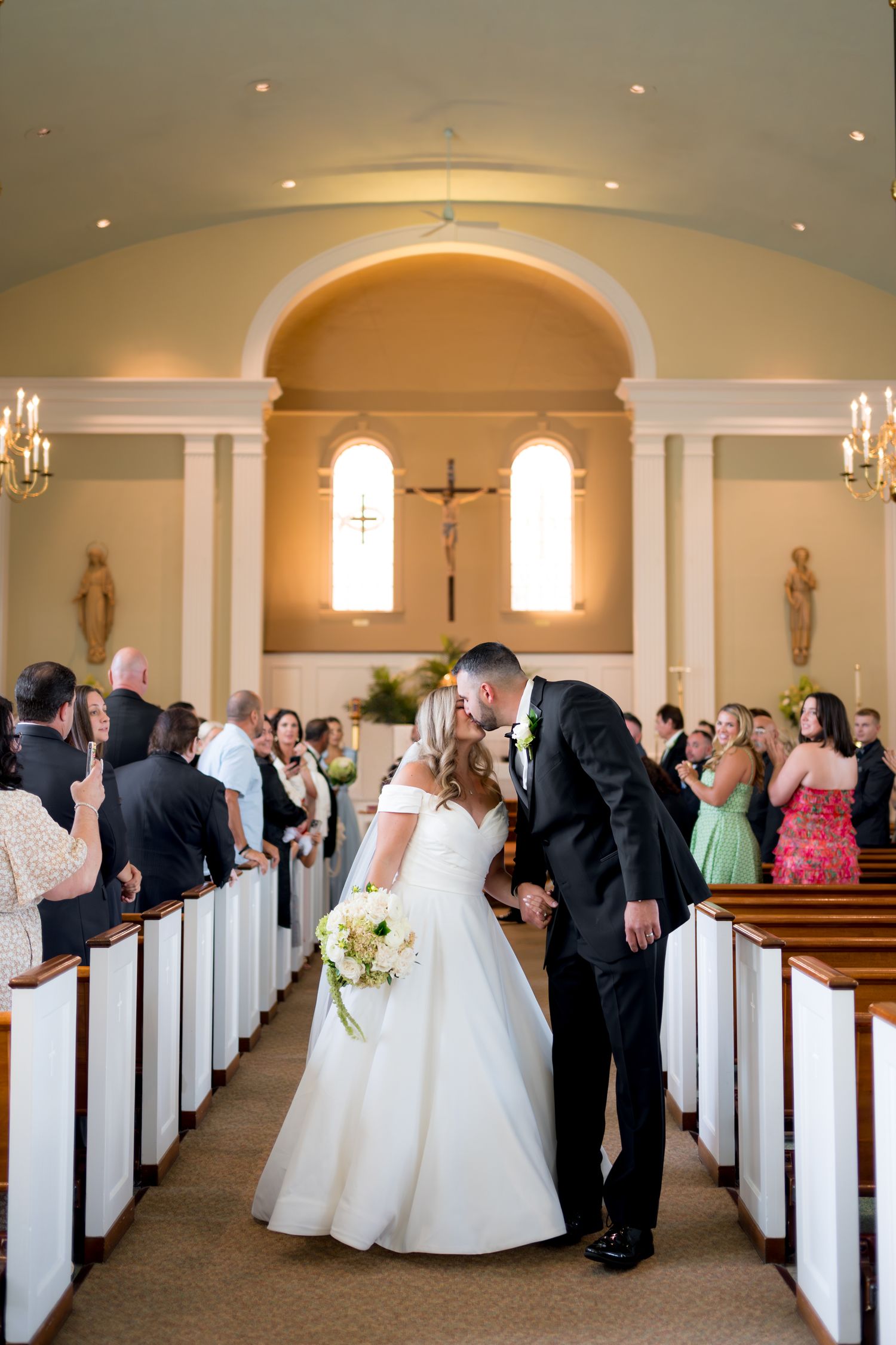 Wedding ceremony panorama in church chapel with white pews and arched ceilings.