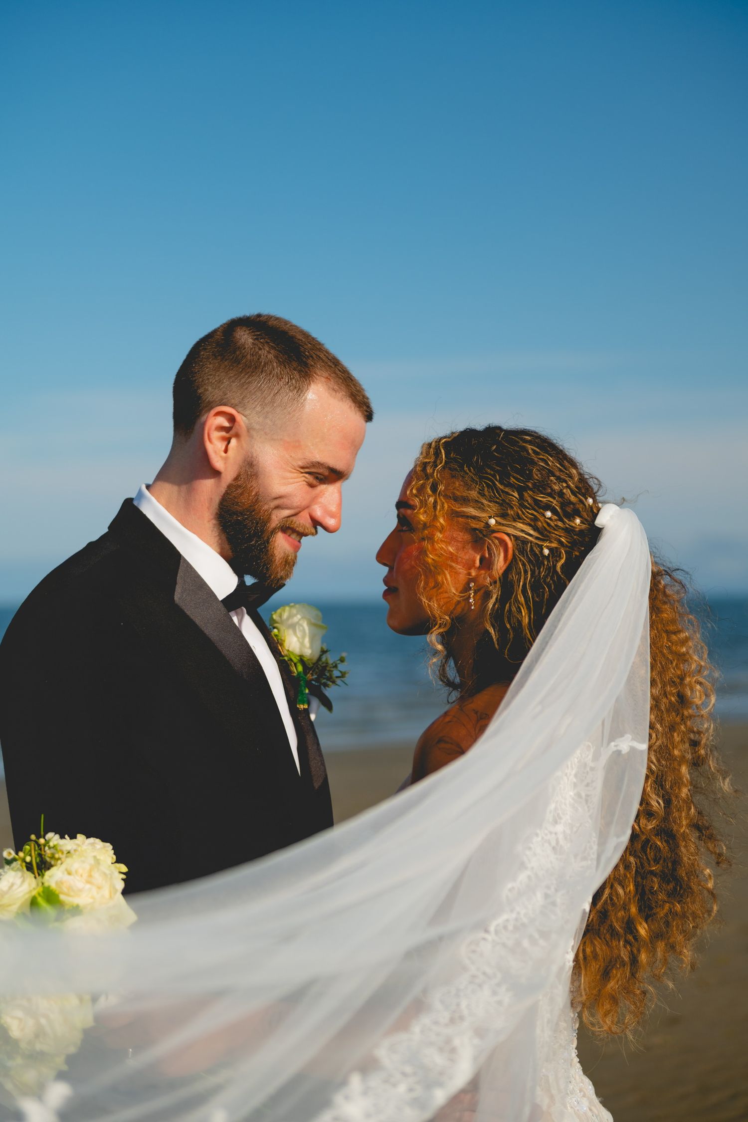 A wedding couple shares intimate moments as the veil flows in the breeze.