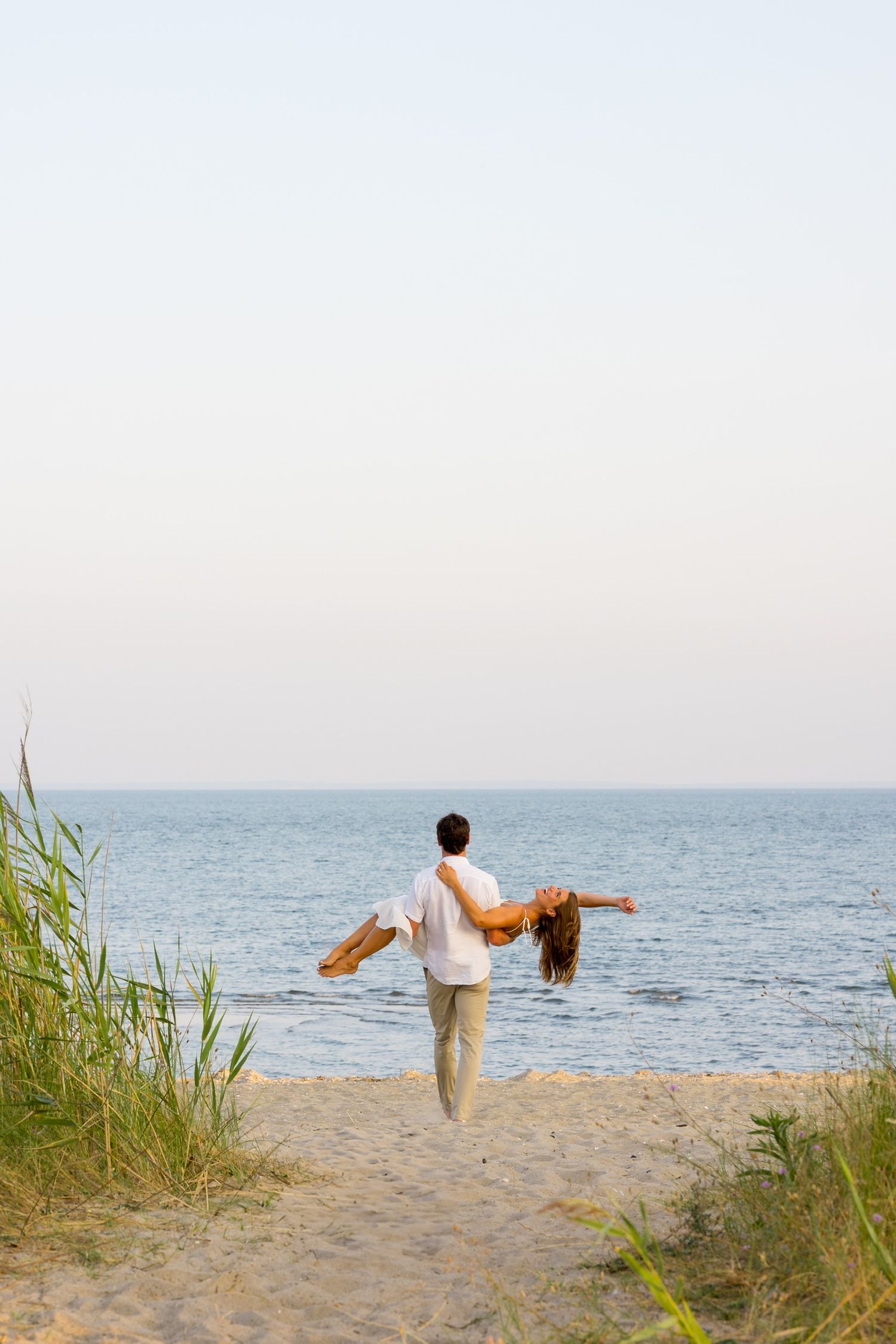 A couple performs a romantic dance lift silhouetted against the ocean in Westport, Connecticut.