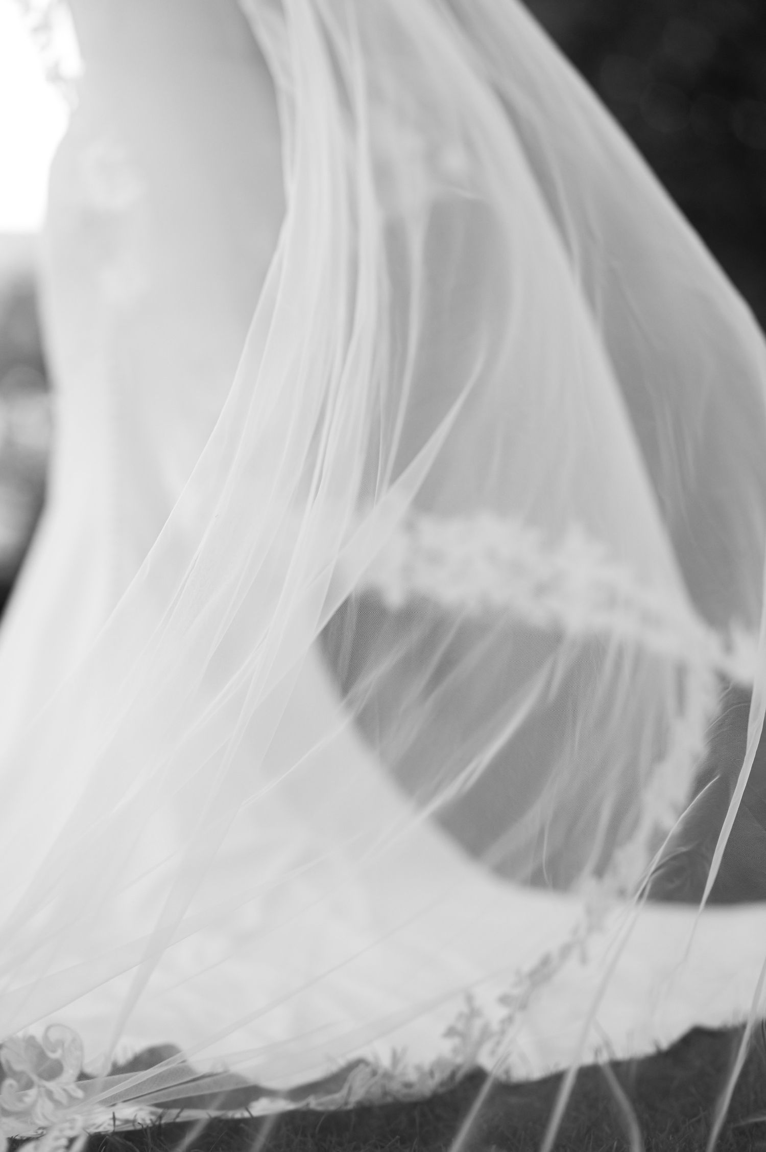 Flowing white veil fabric creates ethereal movement against dark background.