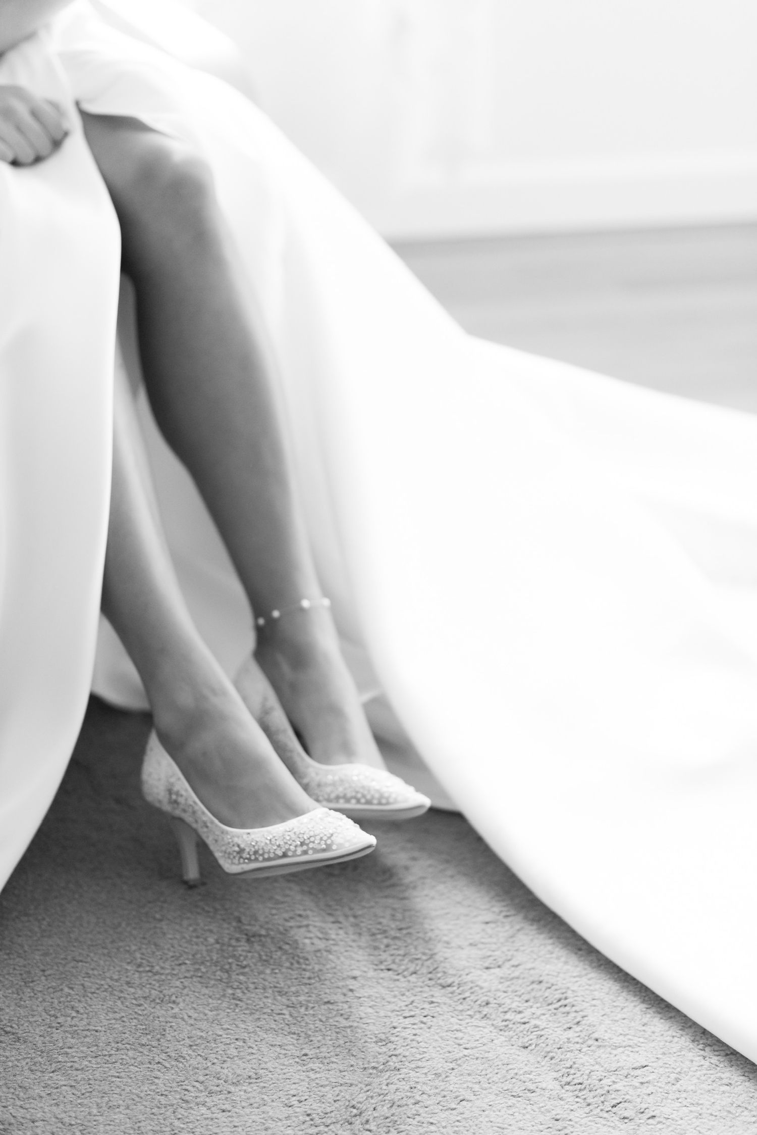 Black and white detail shot of bride's feet and wedding dress hem.
