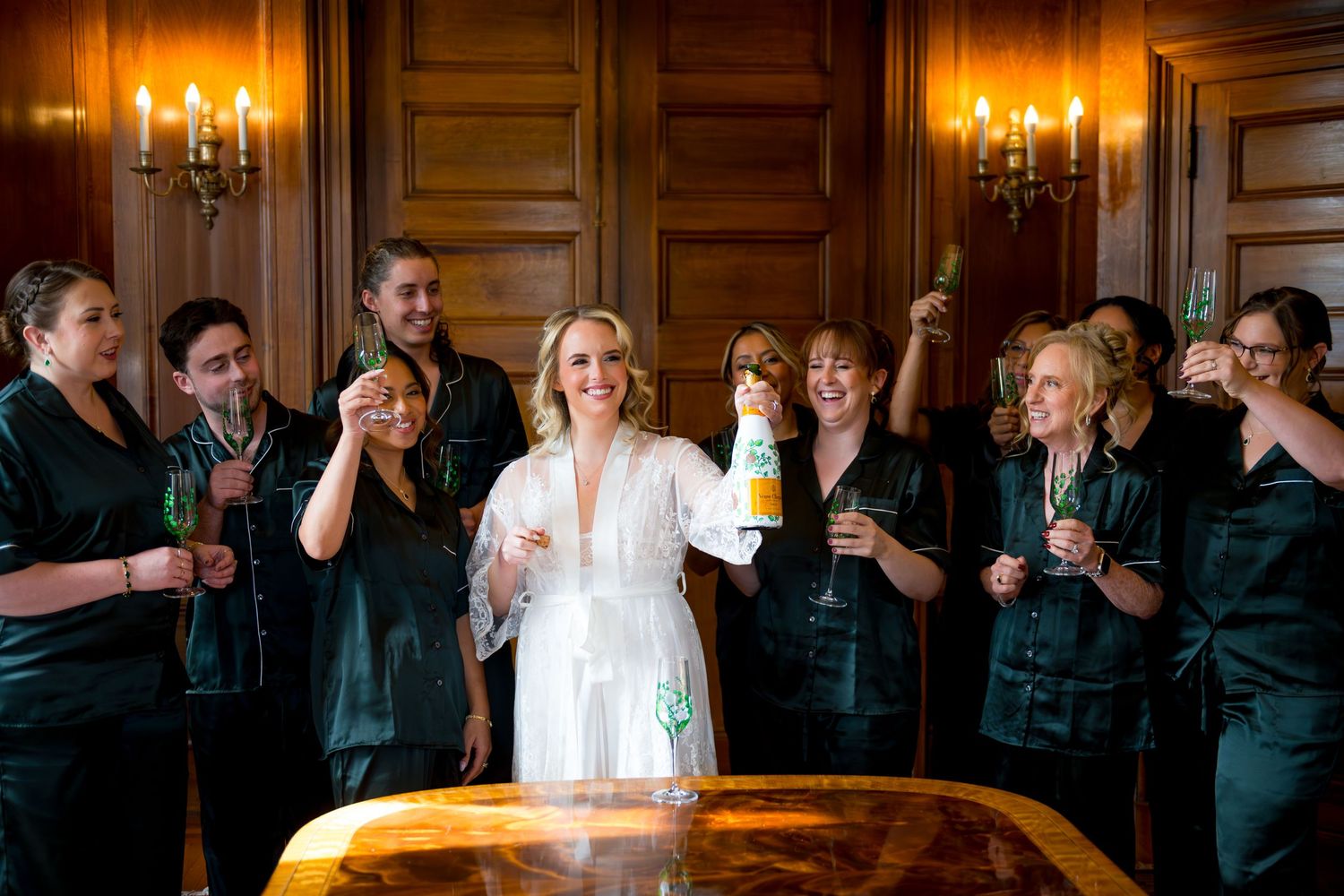 A group of people in formal attire toasting with champagne glasses in an elegant room with chandelier lighting.