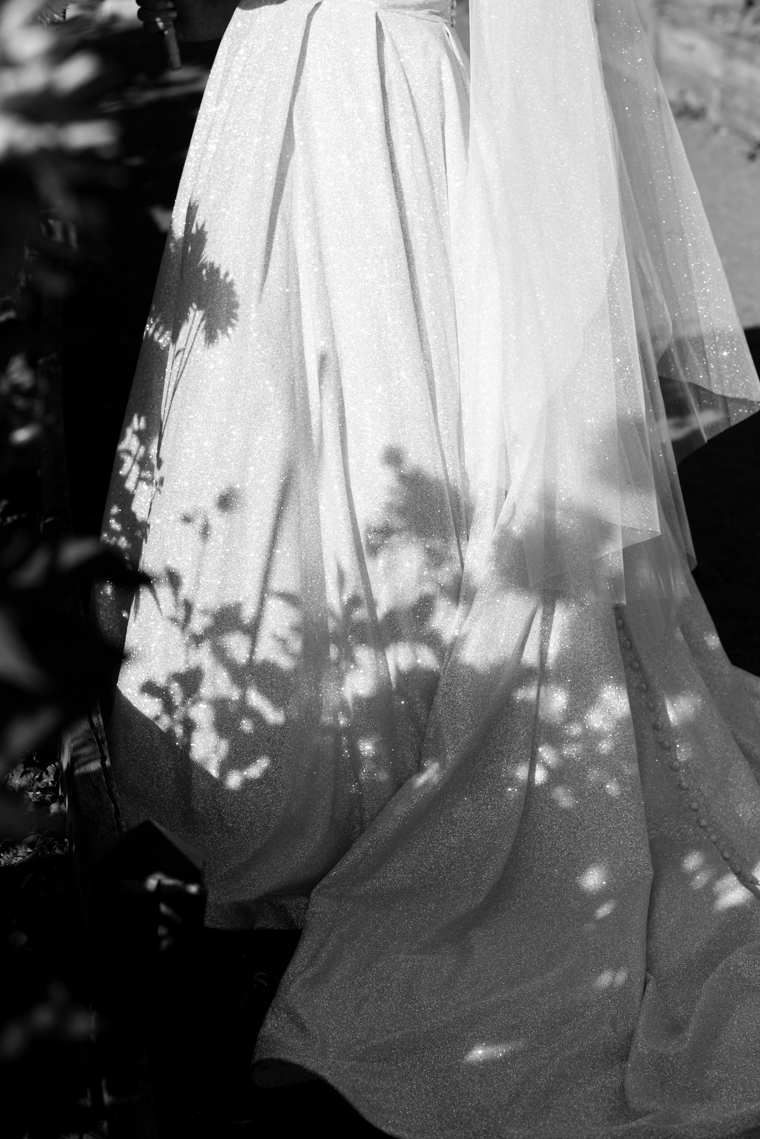 Dappled light creates delicate shadows on a flowing white dress.