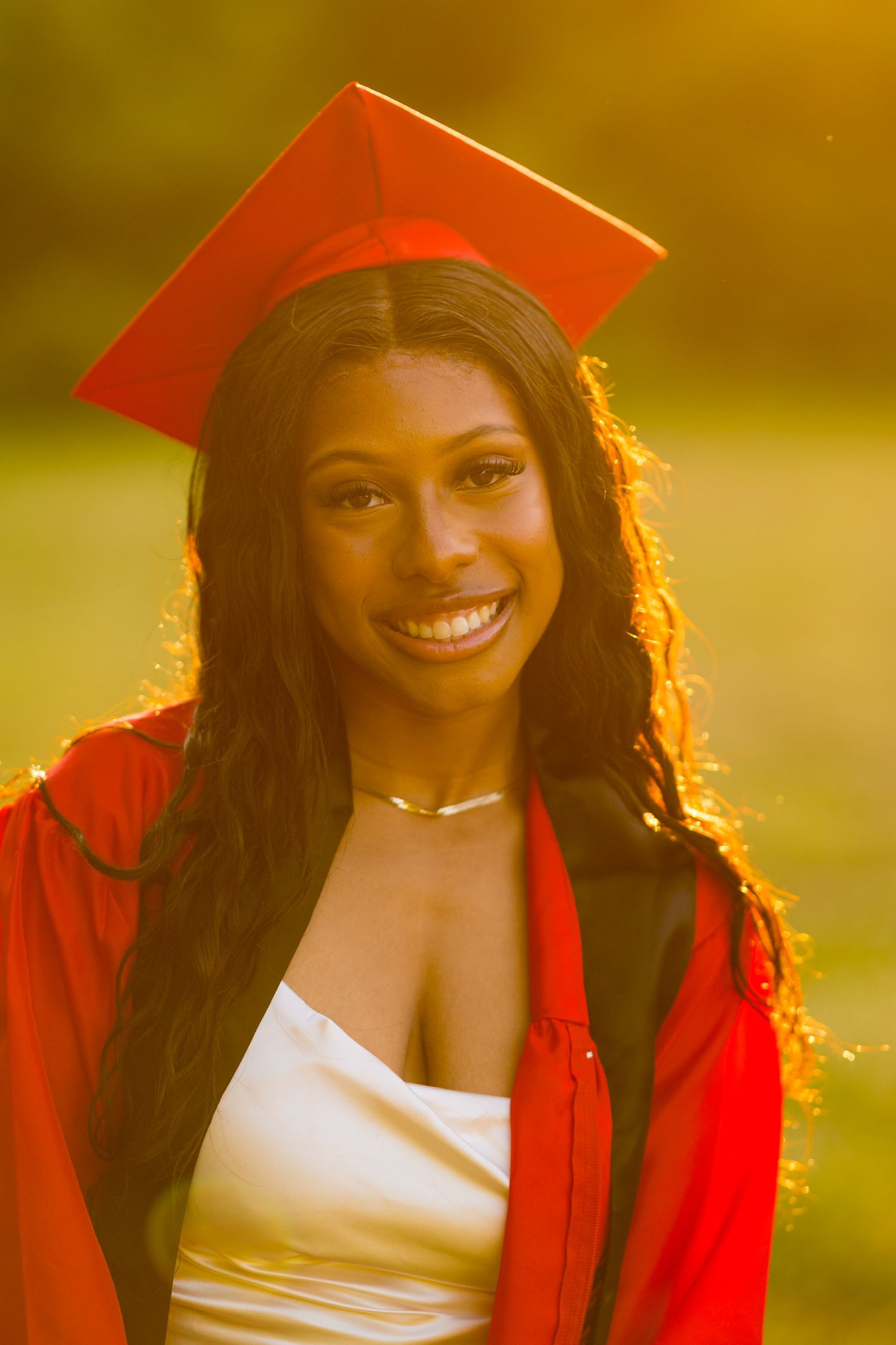 Golden hour graduation portraits in red cap and gown with backlit glow.