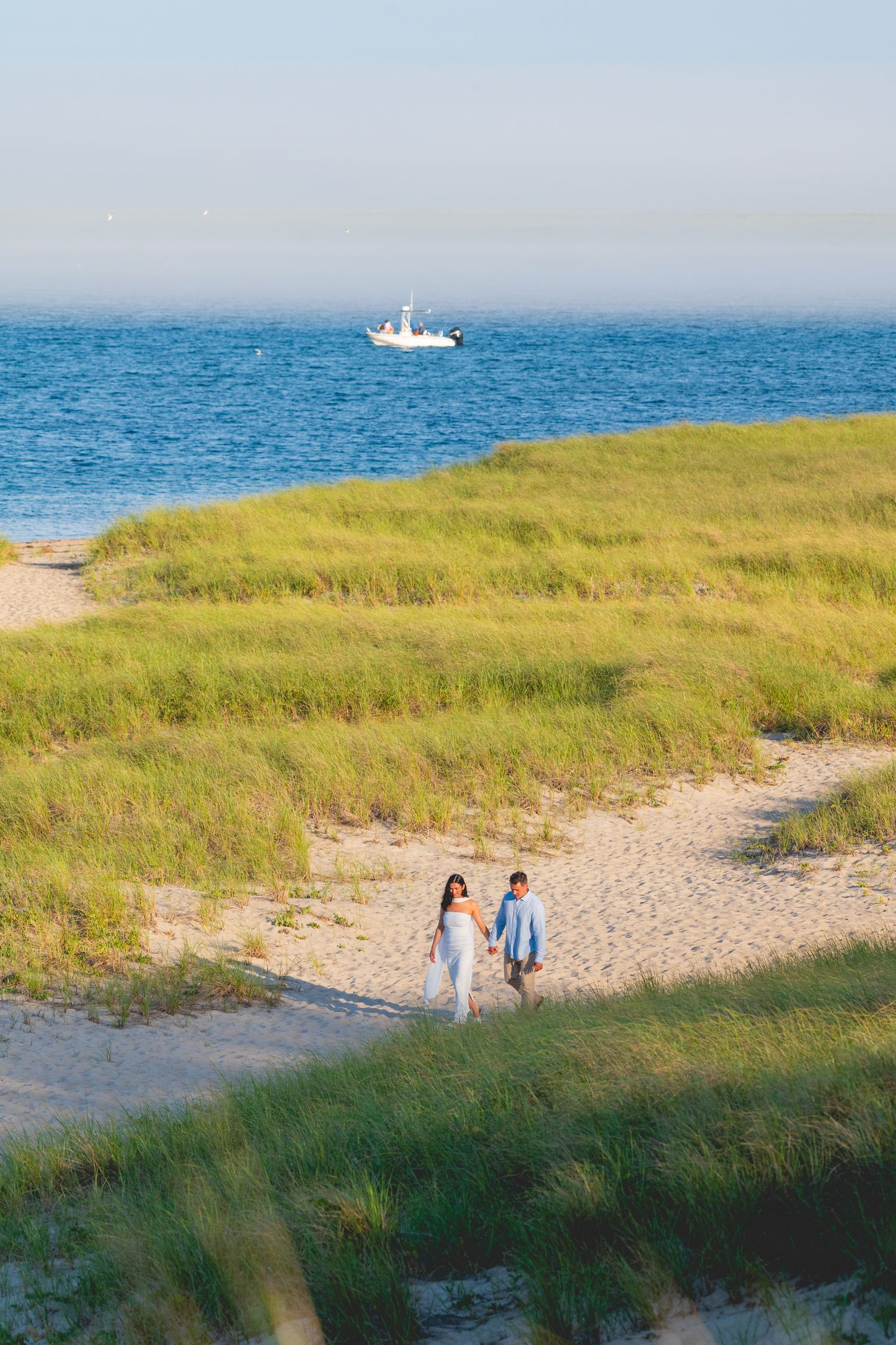 An engagement photoshoot on a scenic Cape Cod beach with dunes and ocean views at sunset.