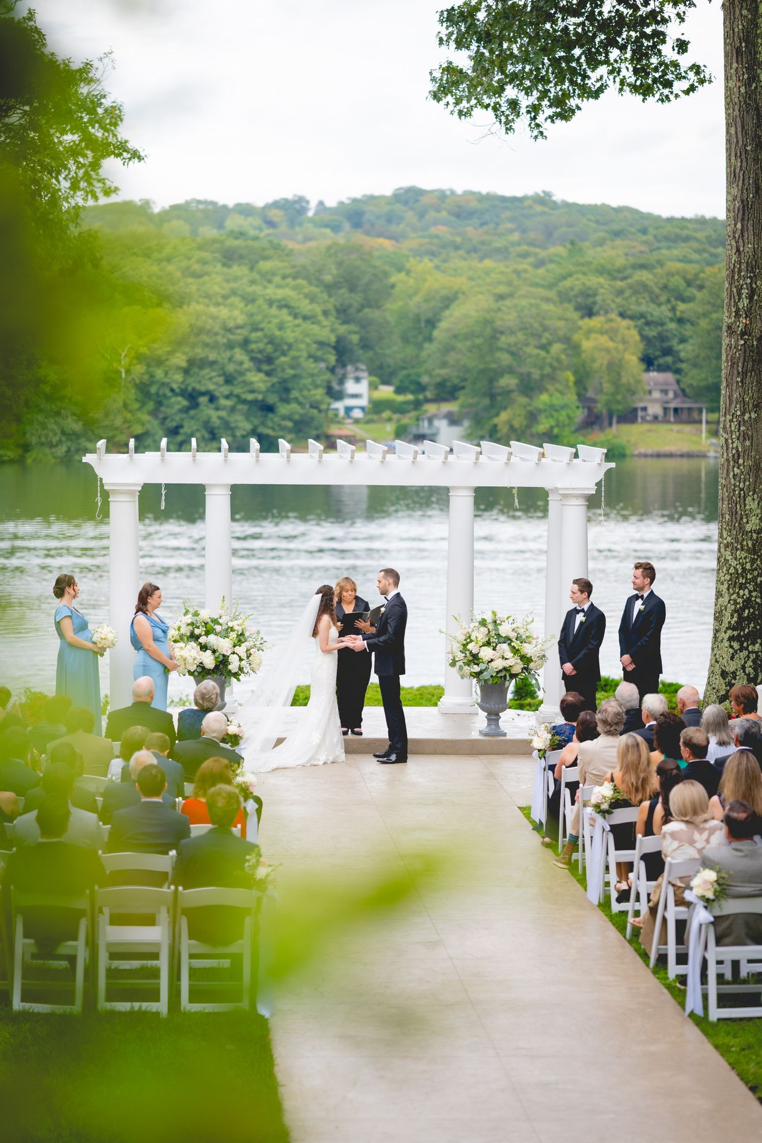 Waterfront wedding ceremony setup with white chairs and floral arrangements overlooking the lake at the Waterview in Connecticut.