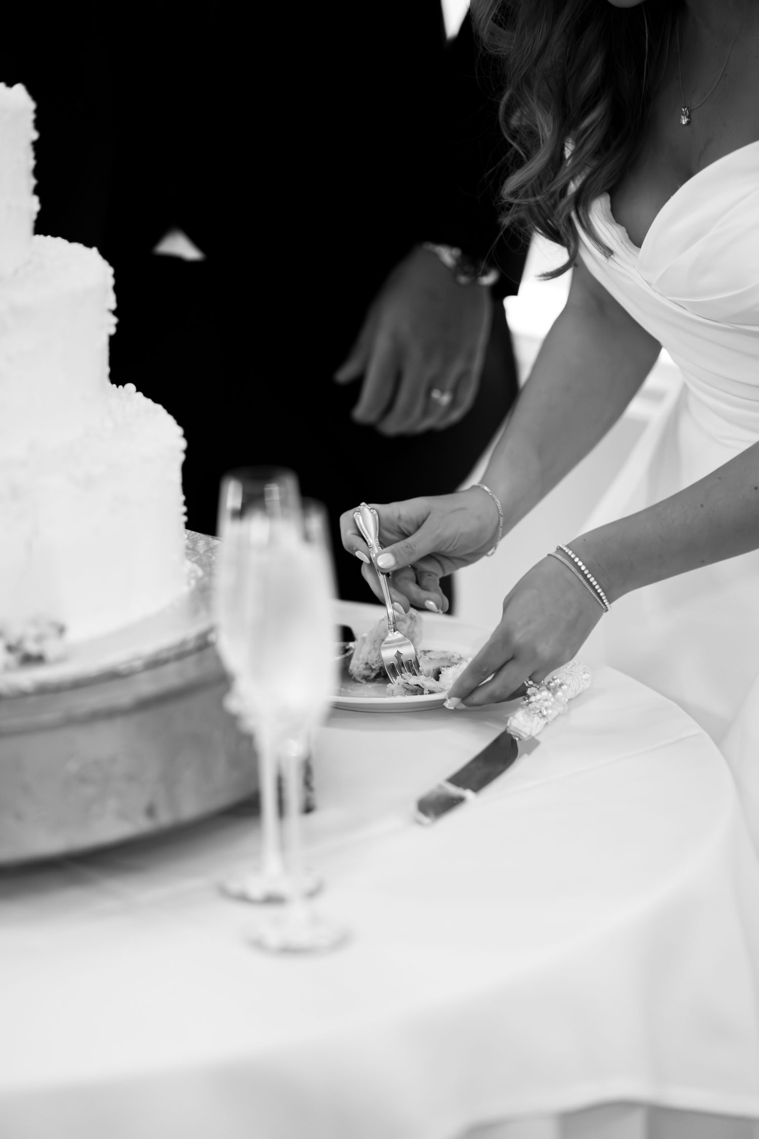 Close-up shots of cutting a white wedding cake in black and white photography.