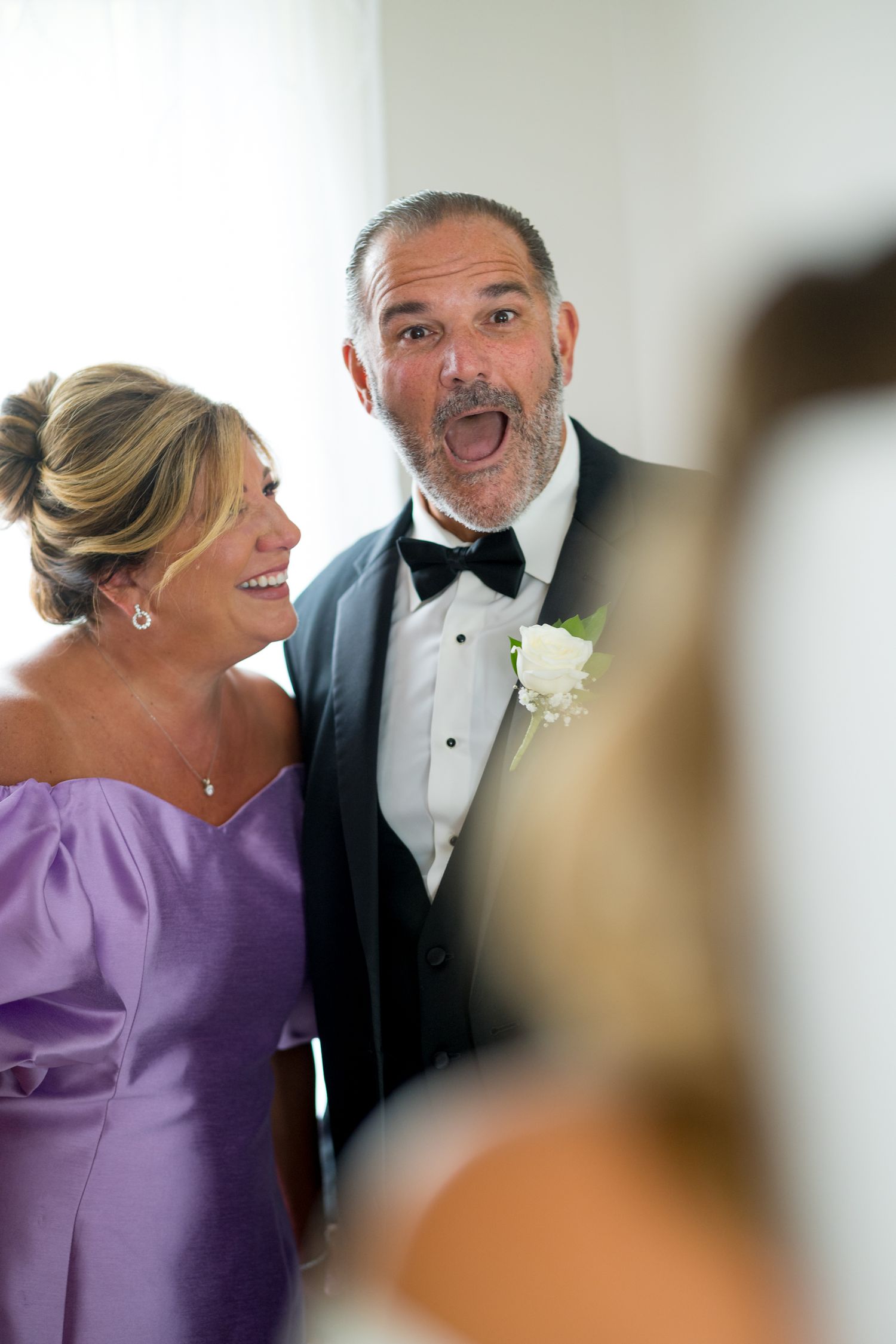 Candid moment of laughter between wedding guests in formal attire.