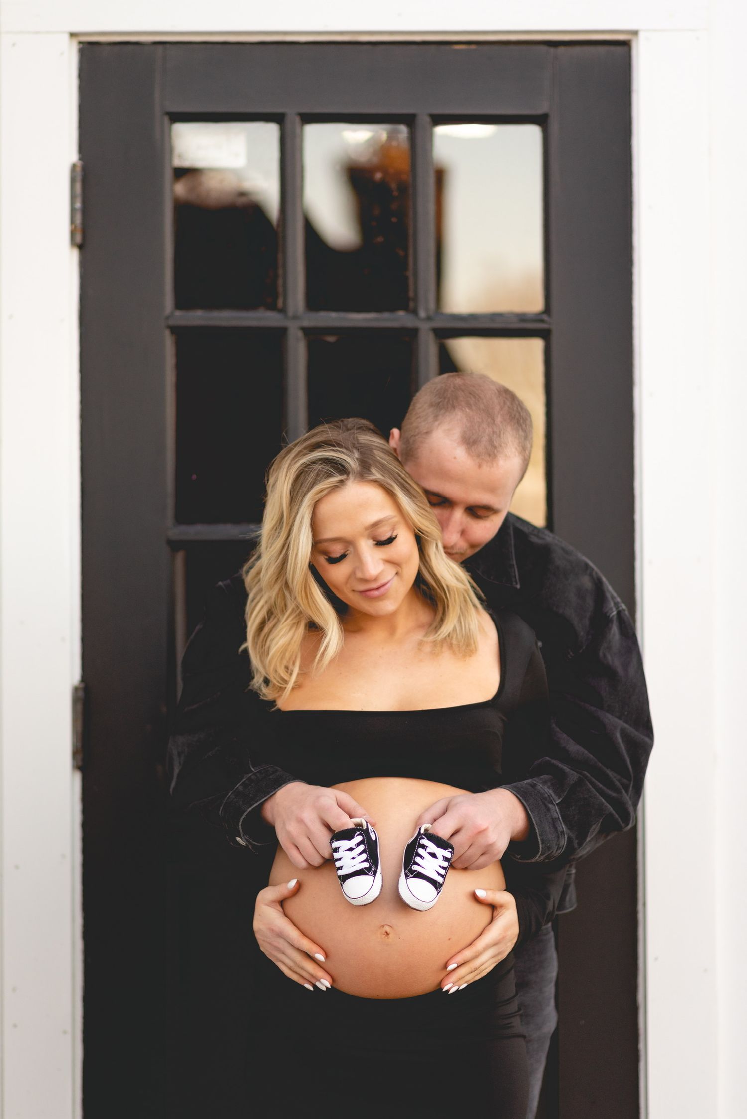 Maternity photos showing a pregnant belly with tiny shoes placed on it.