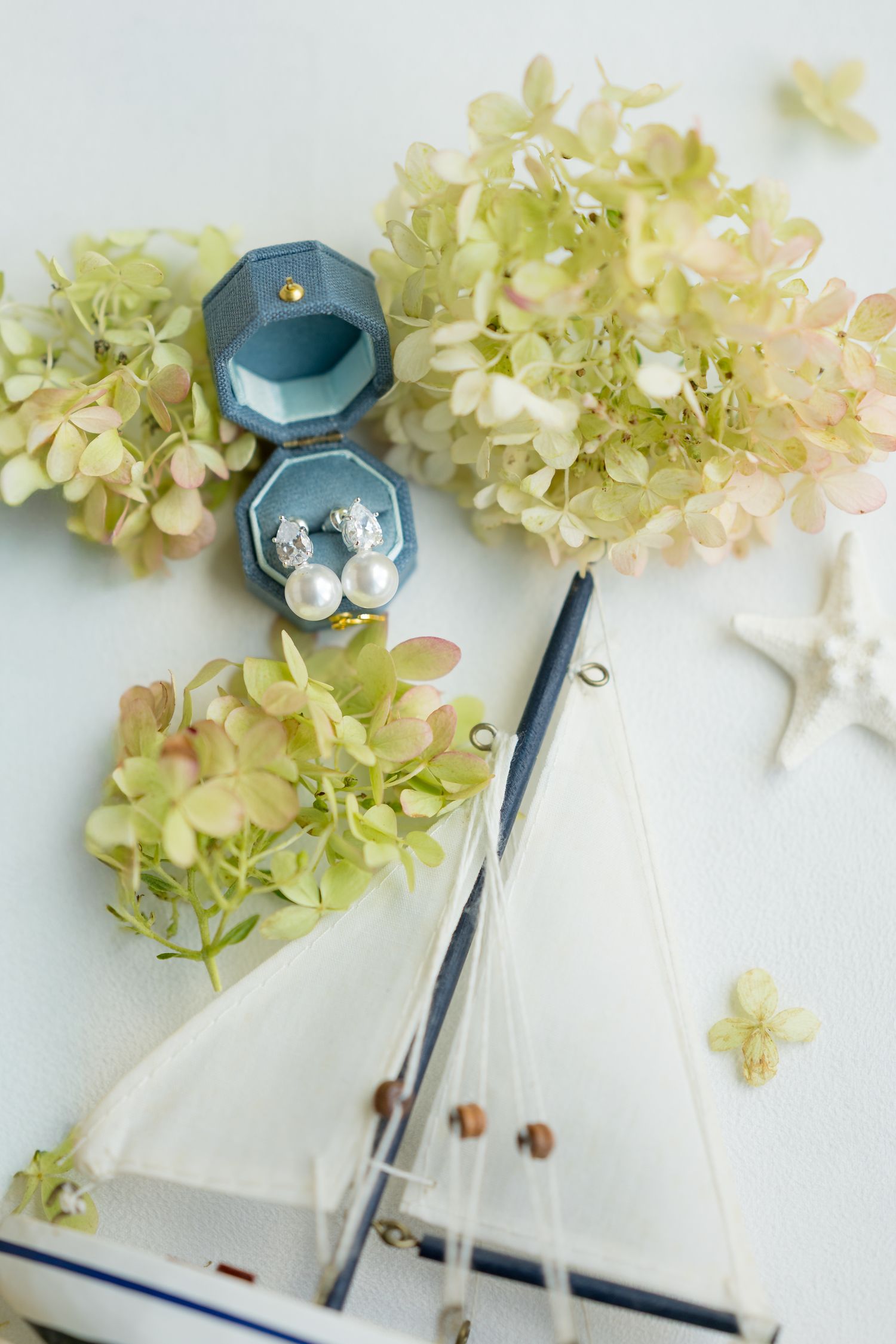 Wedding details with blue cufflinks and delicate hydrangea flowers on white background.