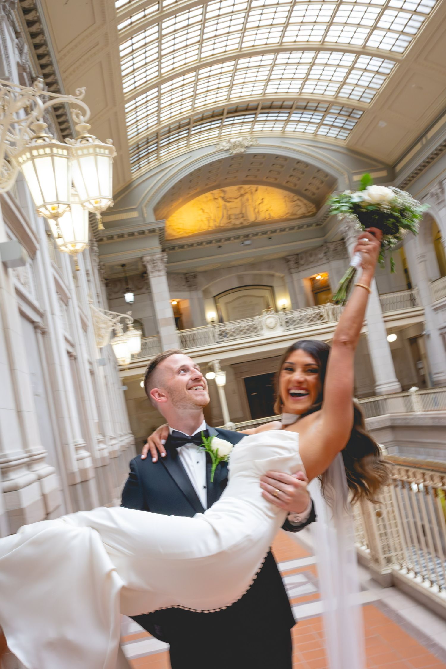Joyful wedding celebration in an elegant marble hallway with vaulted glass ceiling at Hartford City Hall in Connecticut.