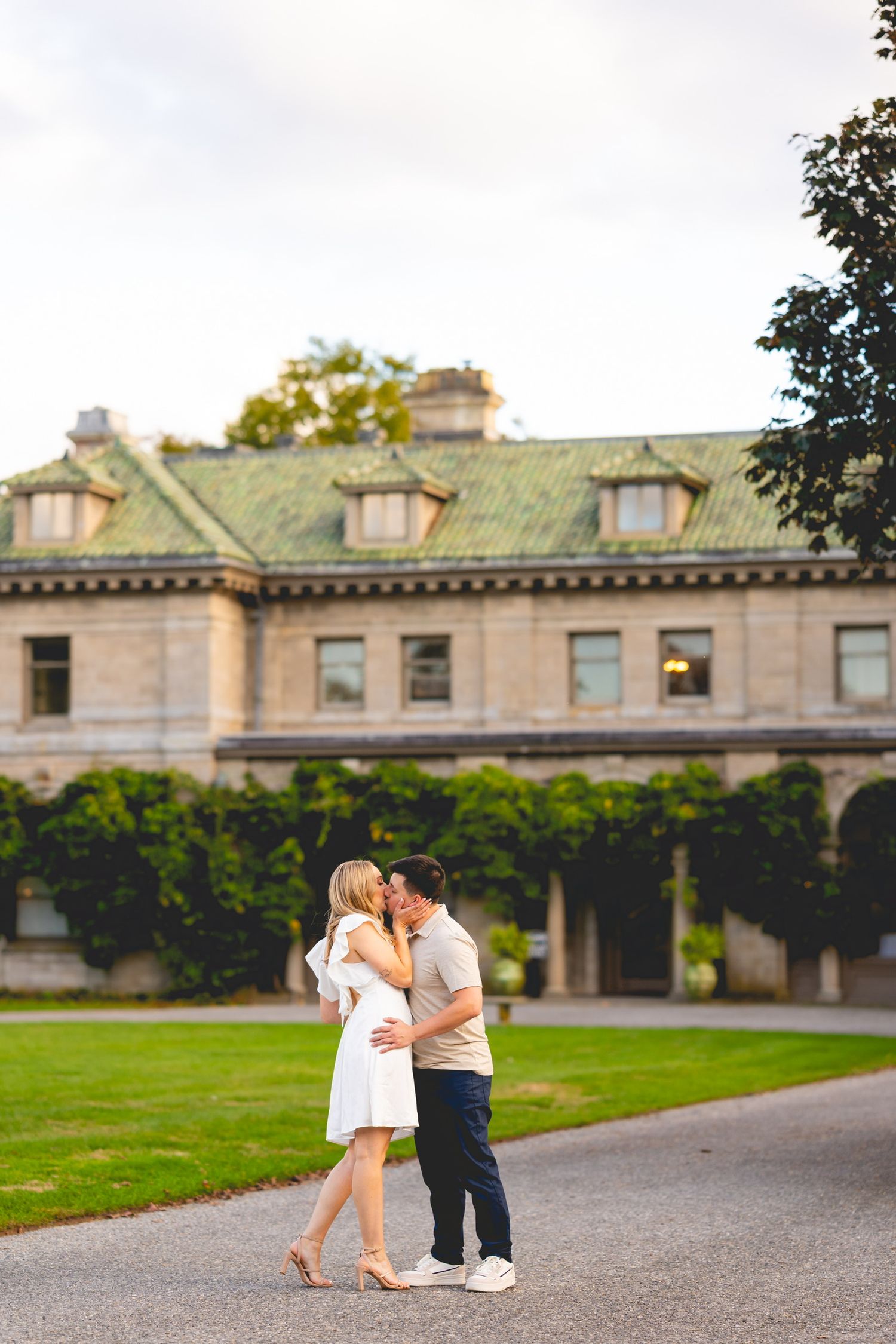 Romantic couple on gravel path in front of historic mansion at Harkness Memorial State Park in Waterford, Connecticut.