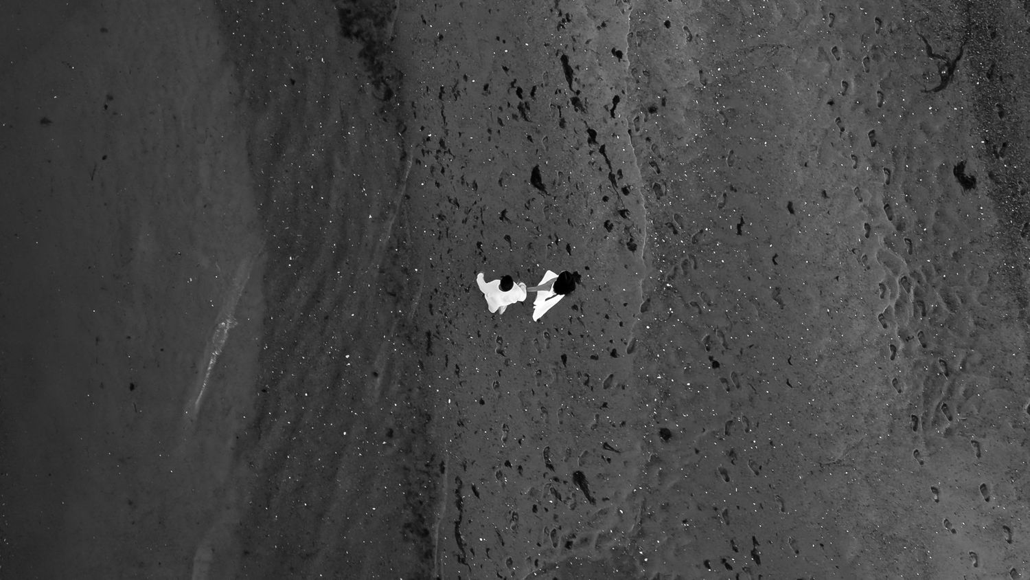 A black and white abstract textured background with rough grunge patterns and dark speckled marks.