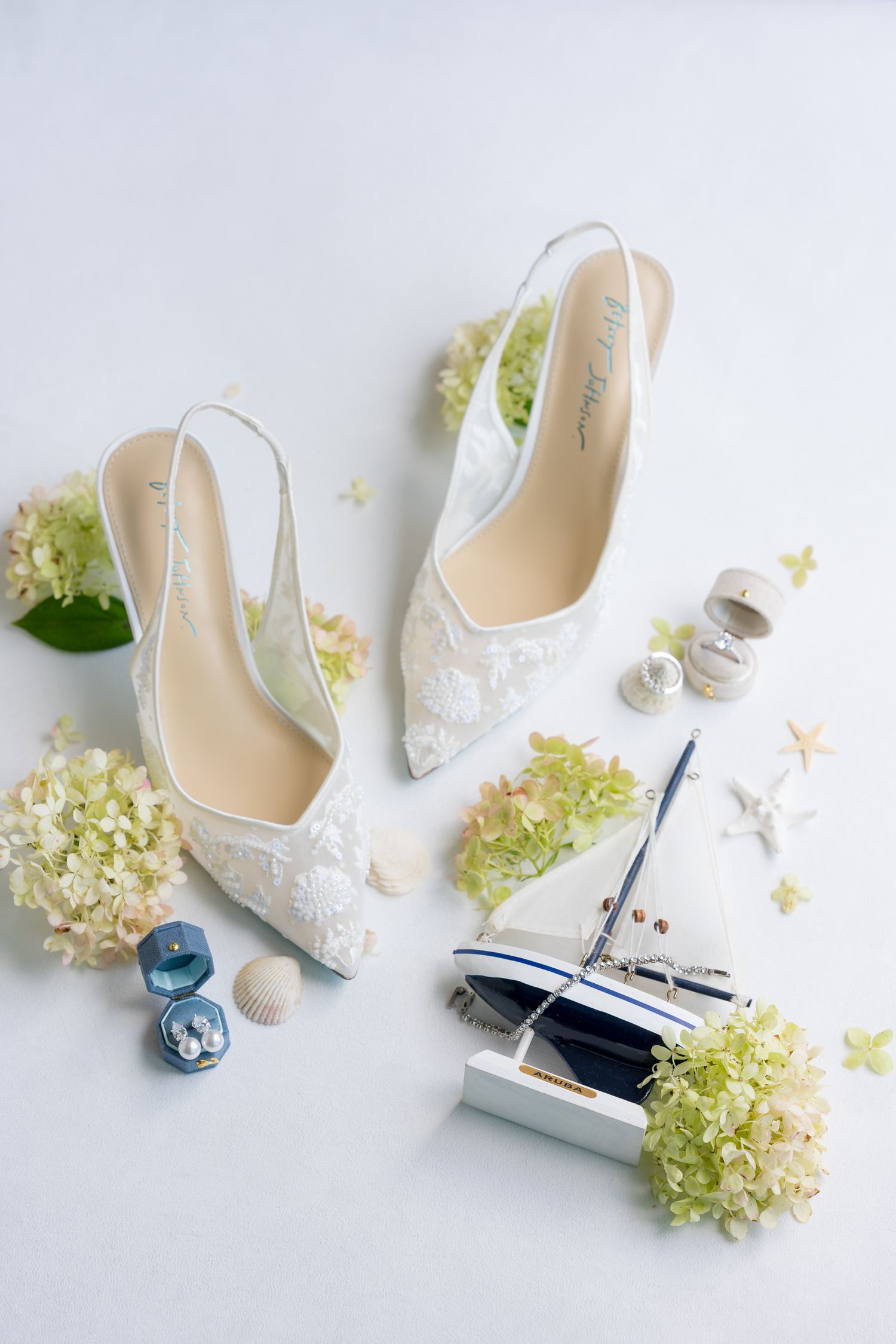 Elegant white lace slingback heels styled with hydrangeas and nautical decor.