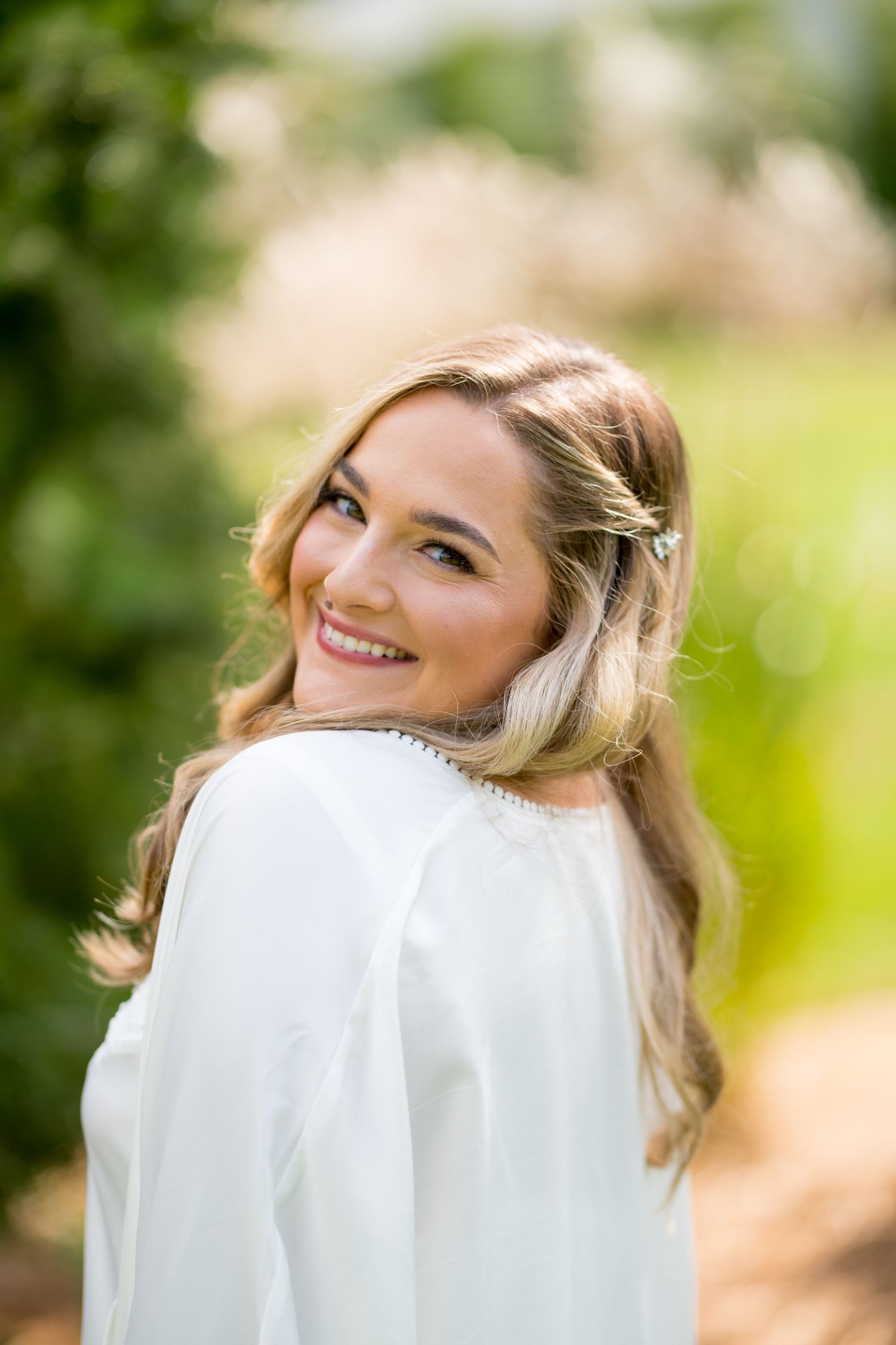 Ethereal bridal portrait with flowing white veil in natural outdoor setting.