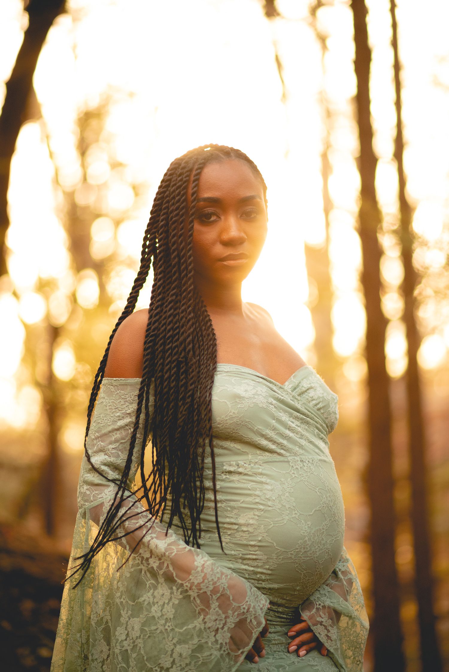 Portrait series of woman in sage dress against golden sunset in forest.