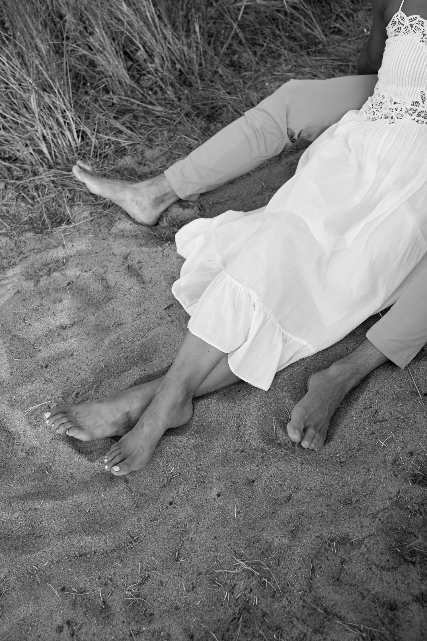 Black and white photo of bare feet in the sand during a beach photoshoot.