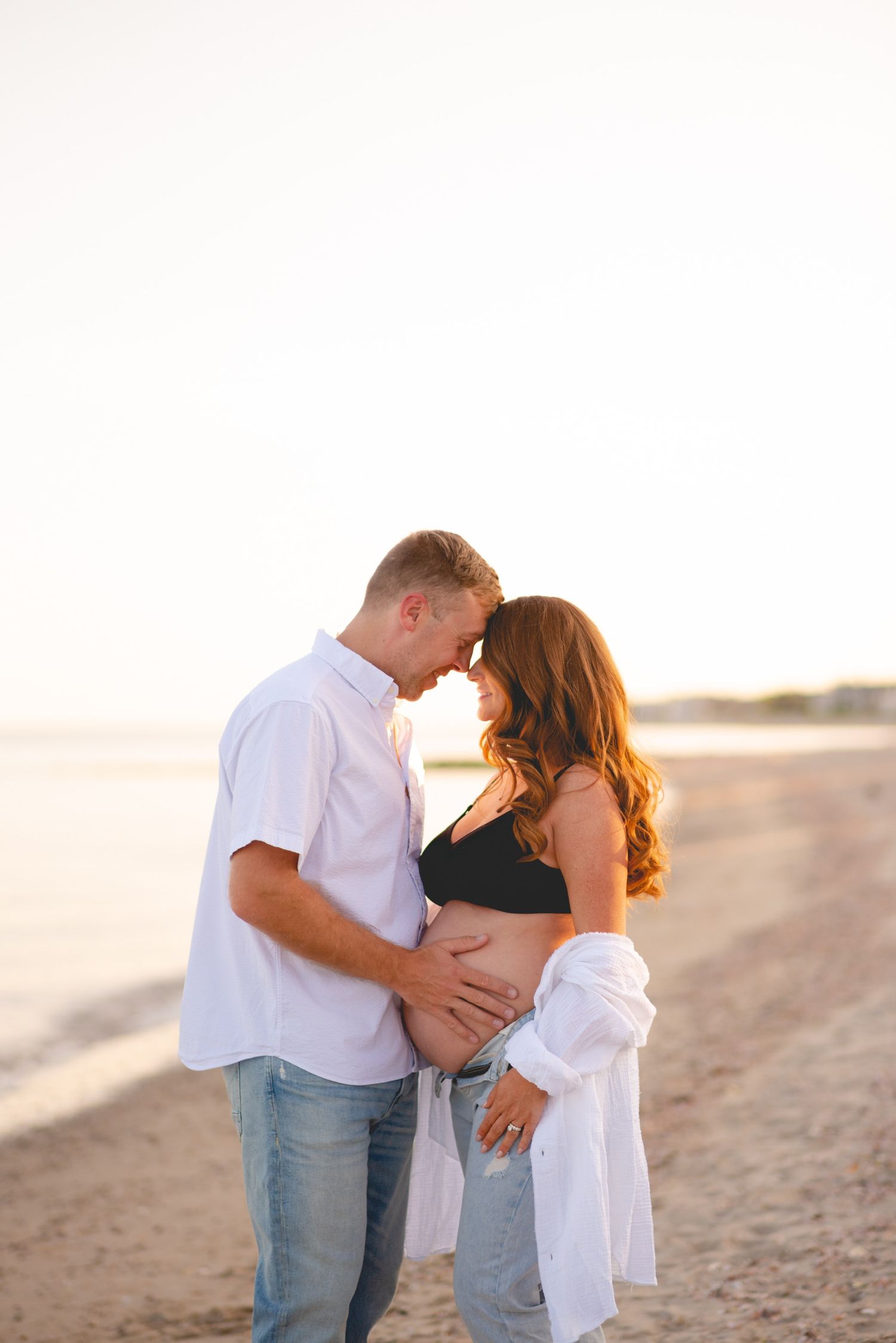 Couple embracing on a sandy beach during sunset.