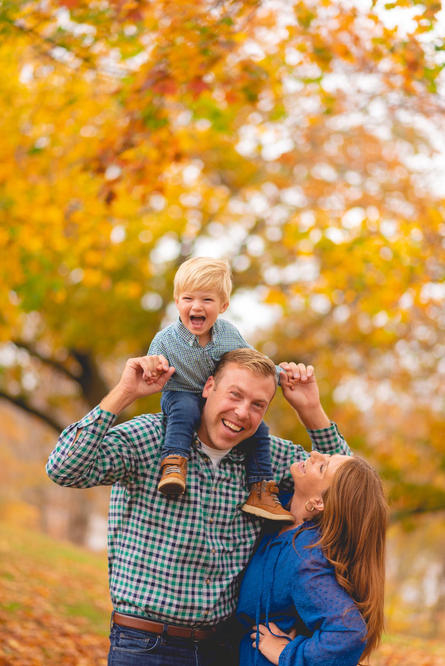 Family playing together under vibrant orange fall foliage.