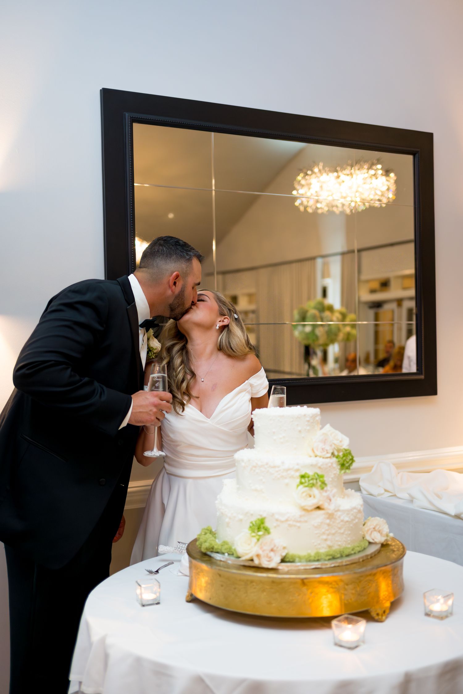 Wedding couple sharing cake cutting moment by elegant tiered white cake.