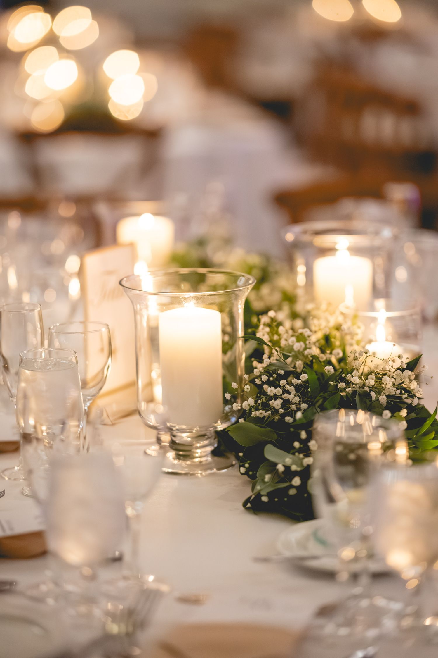 Elegant wedding reception table setting with glowing candles and baby's breath centerpieces.