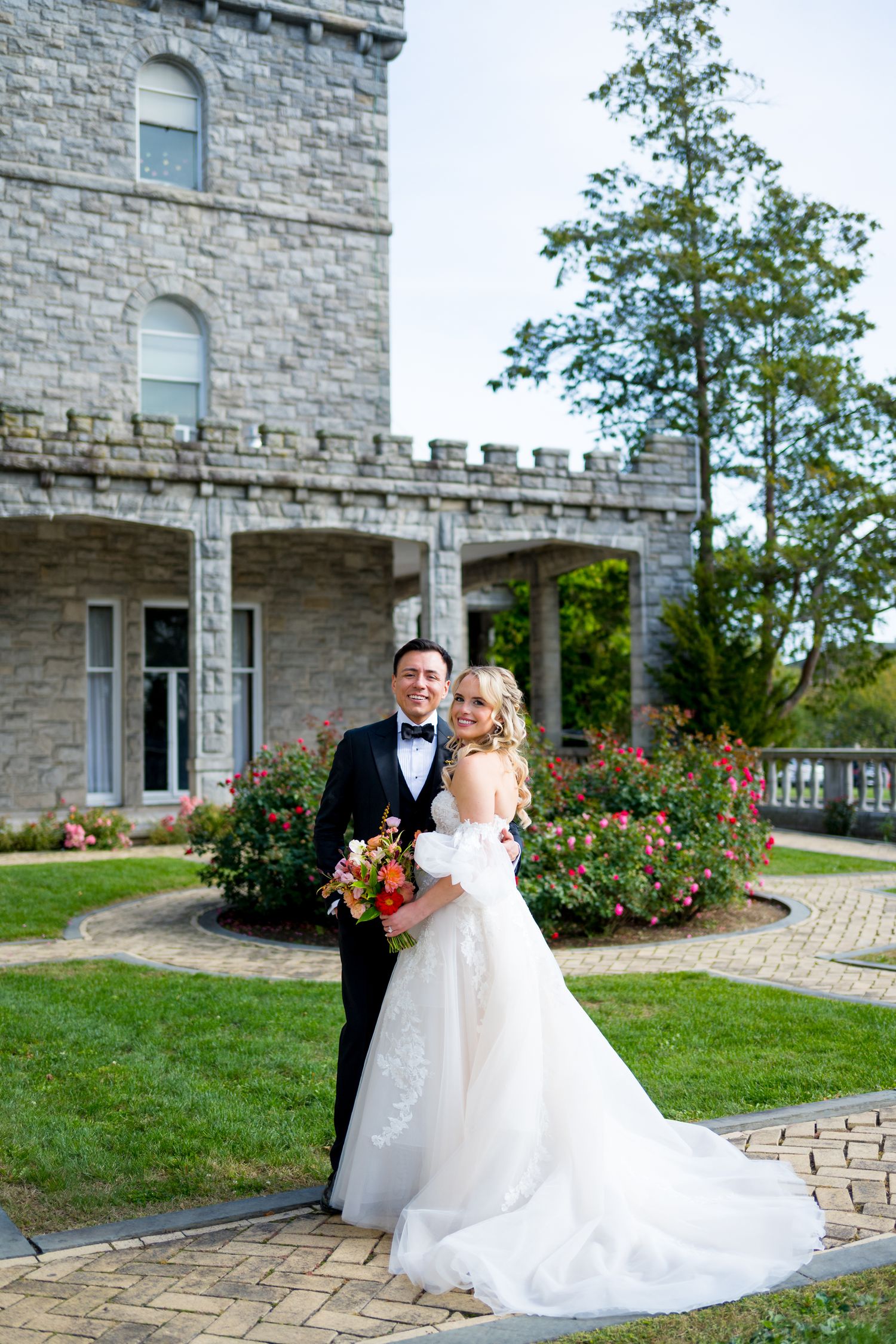 A romantic wedding photoshoot outside a stone castle with beautiful landscaping and brick pathways.