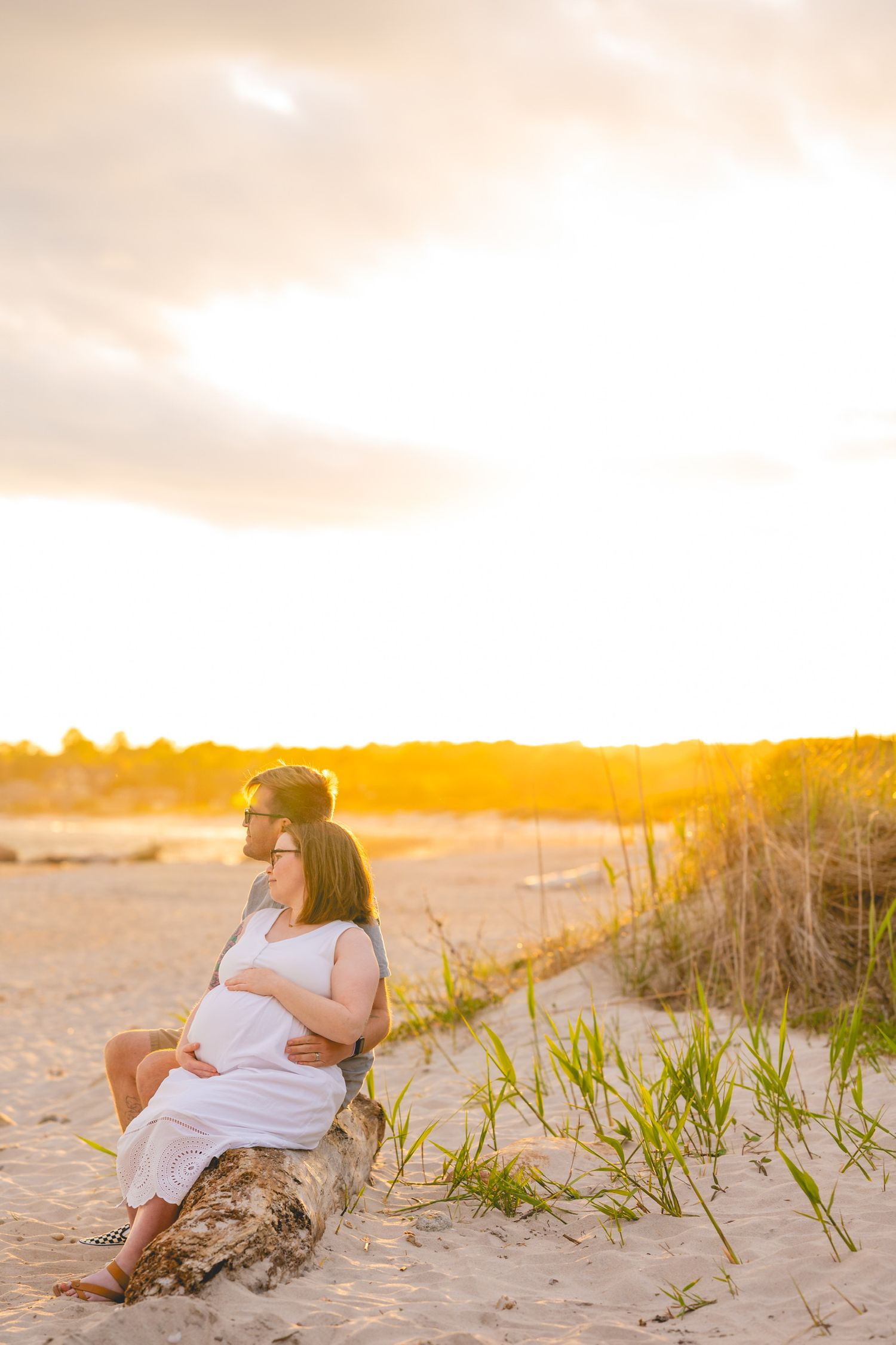 People relaxing on sandy beach dunes at golden sunset.