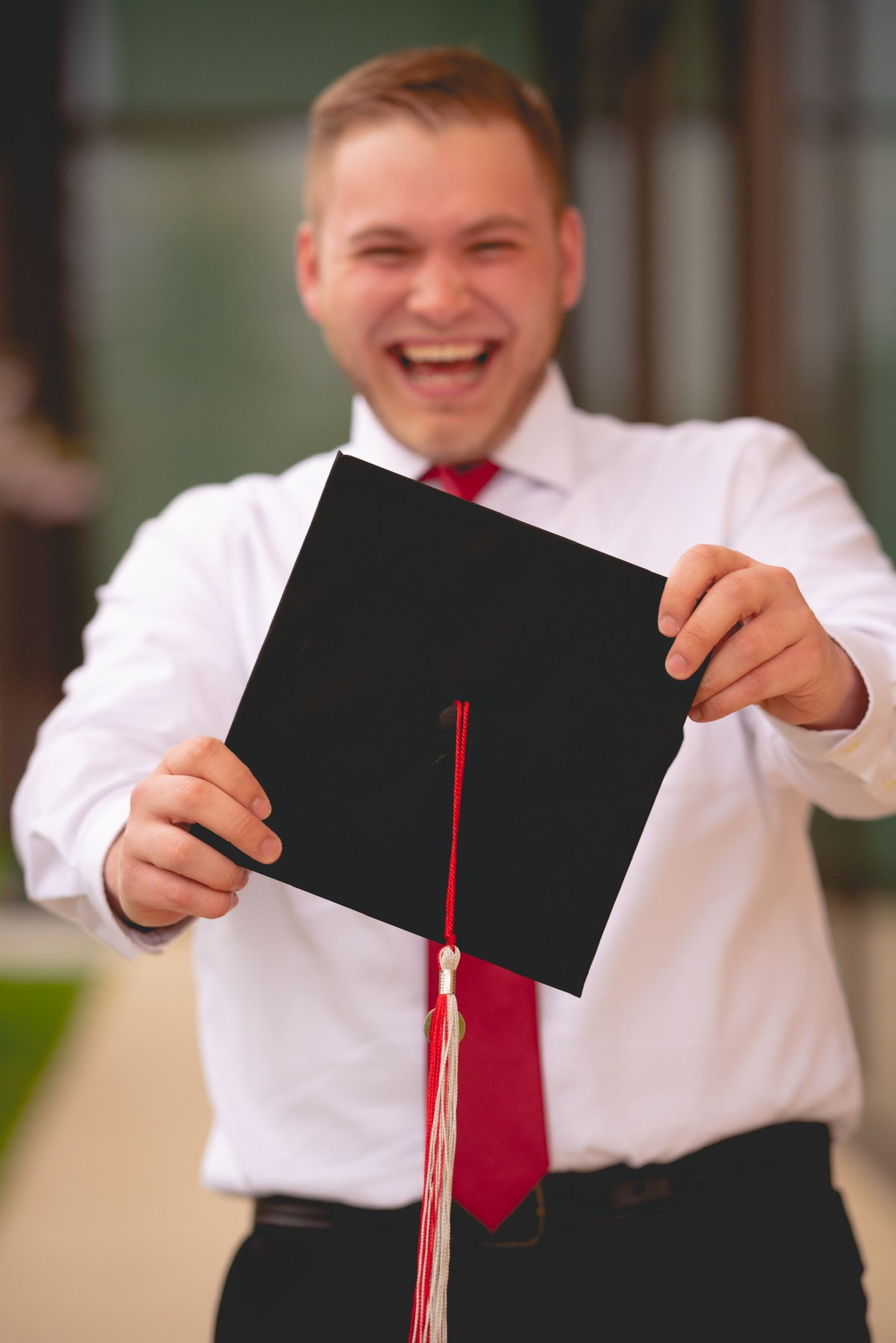 A series of photos showing someone in a white shirt holding up a graduation cap with a red tassel.