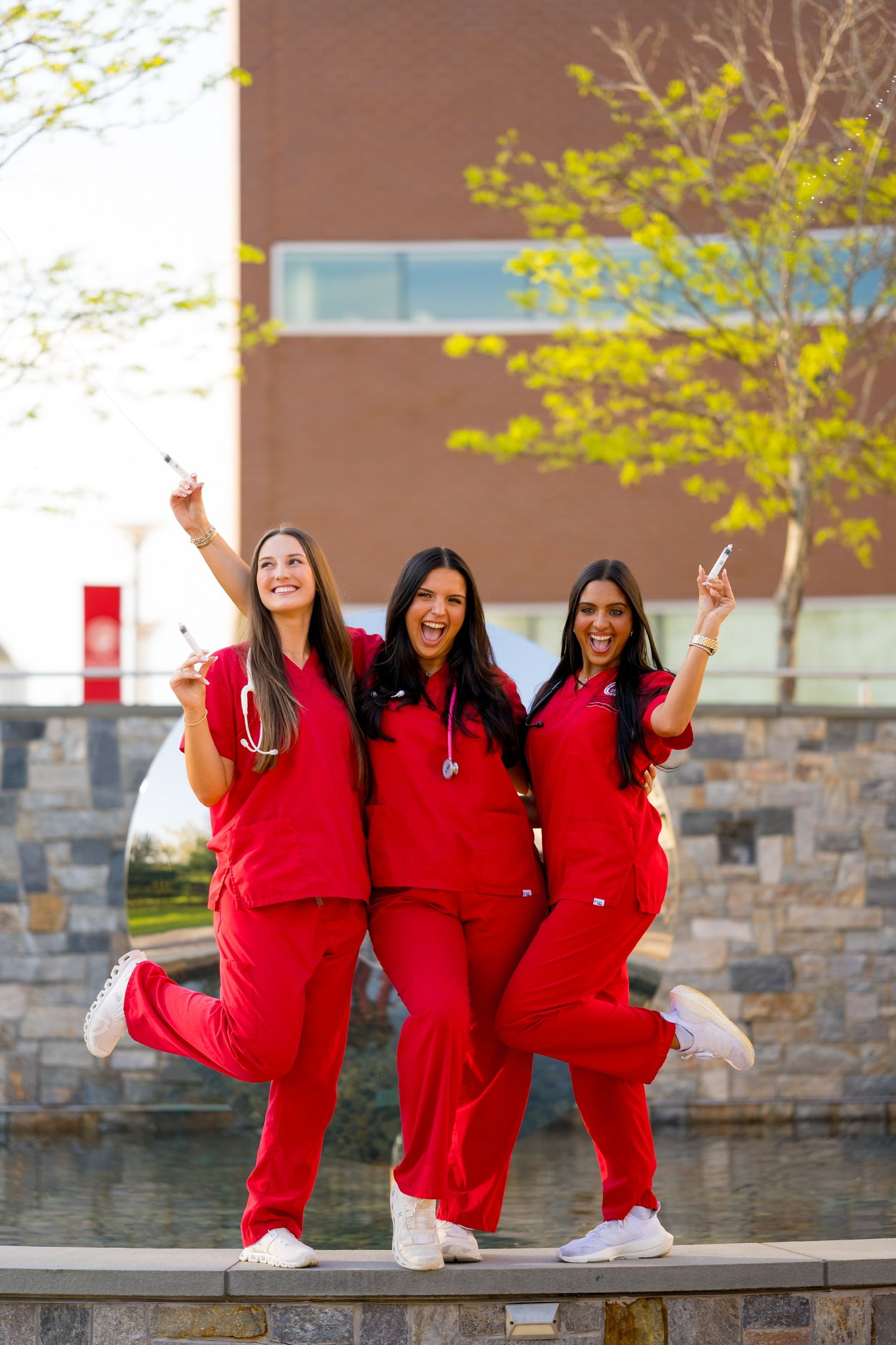 Sacred Heart nursing graduates in red scrubs for graduation photos.