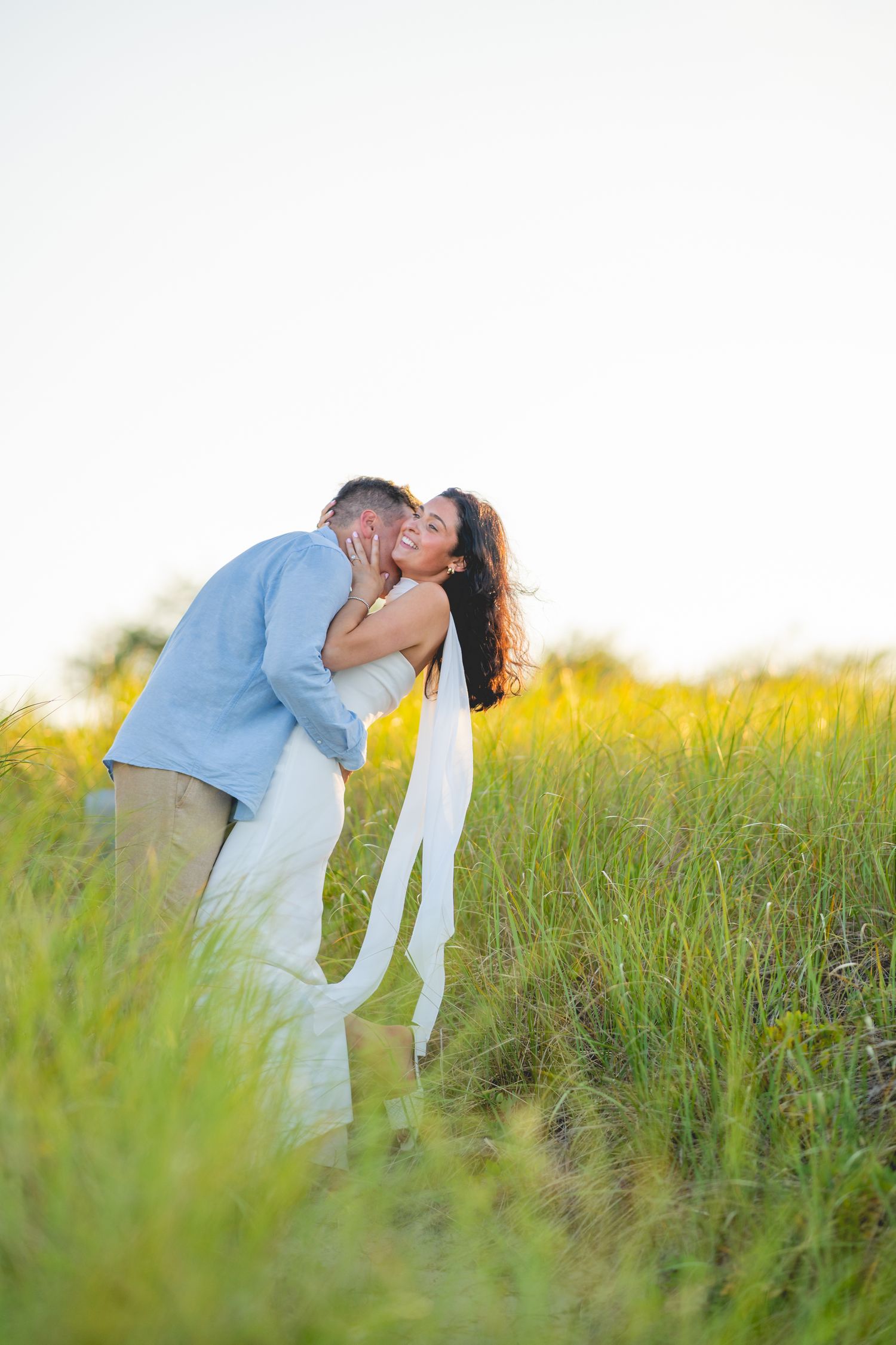 Couple shares intimate moment in Cape Cod at golden hour.