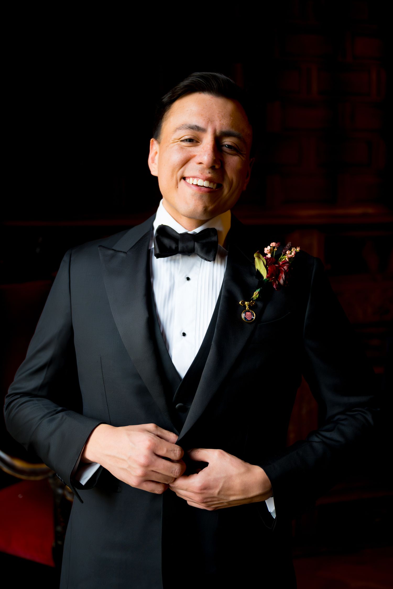 Black and white portraits in a tuxedo with dramatic lighting and boutonniere on wedding day.