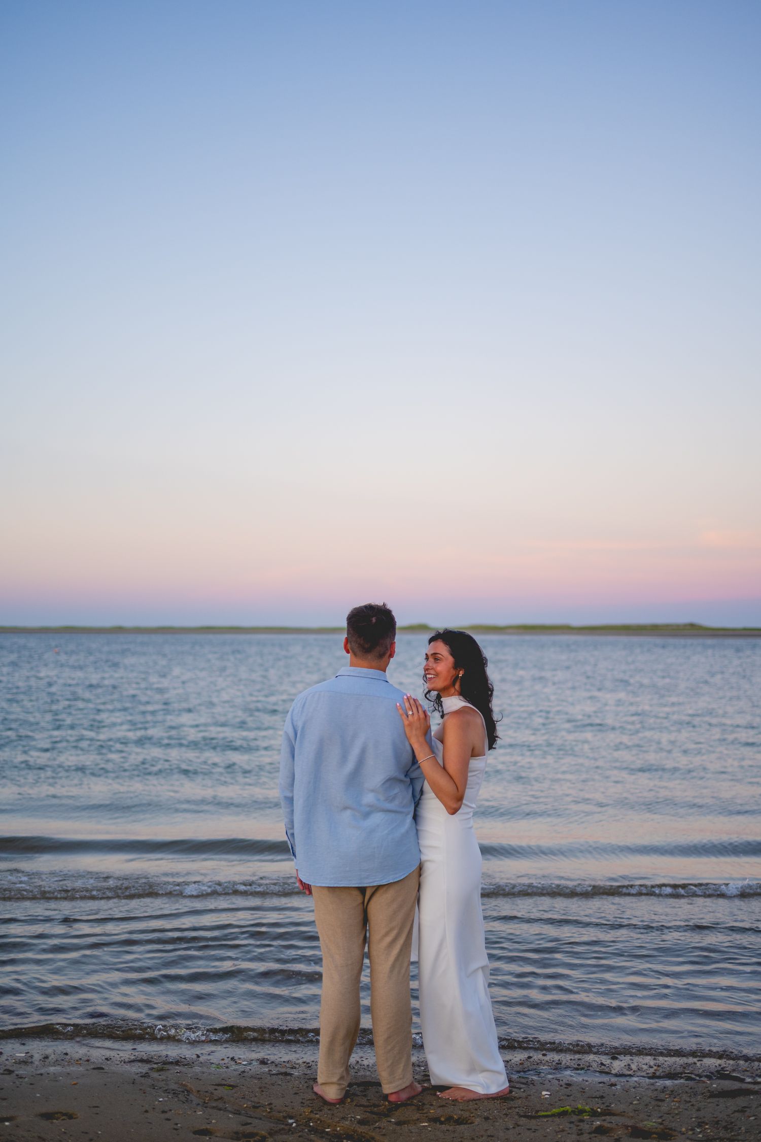 Couple standing together watching the ocean at dusk in Cape Cod.