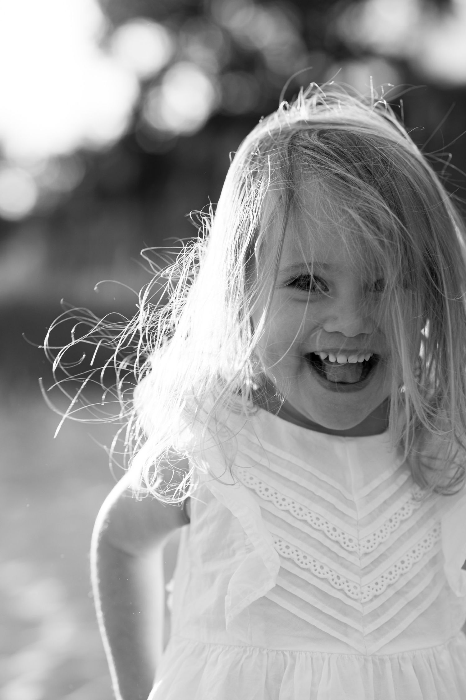 Black and white portrait of person in white lace dress with windswept hair for family photoshoot.