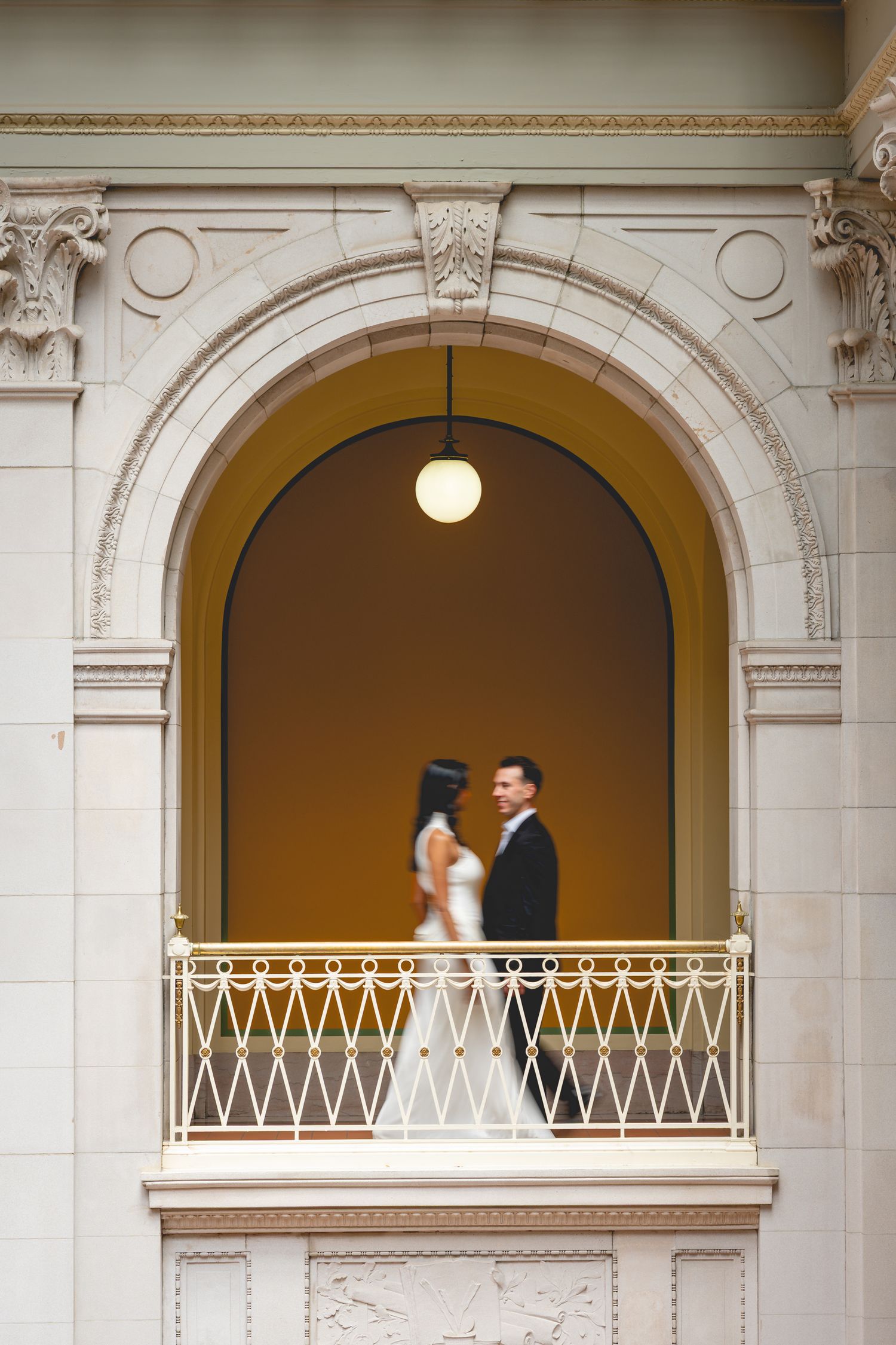A couple shares a romantic moment in arched balconies of Hartford City Hall.