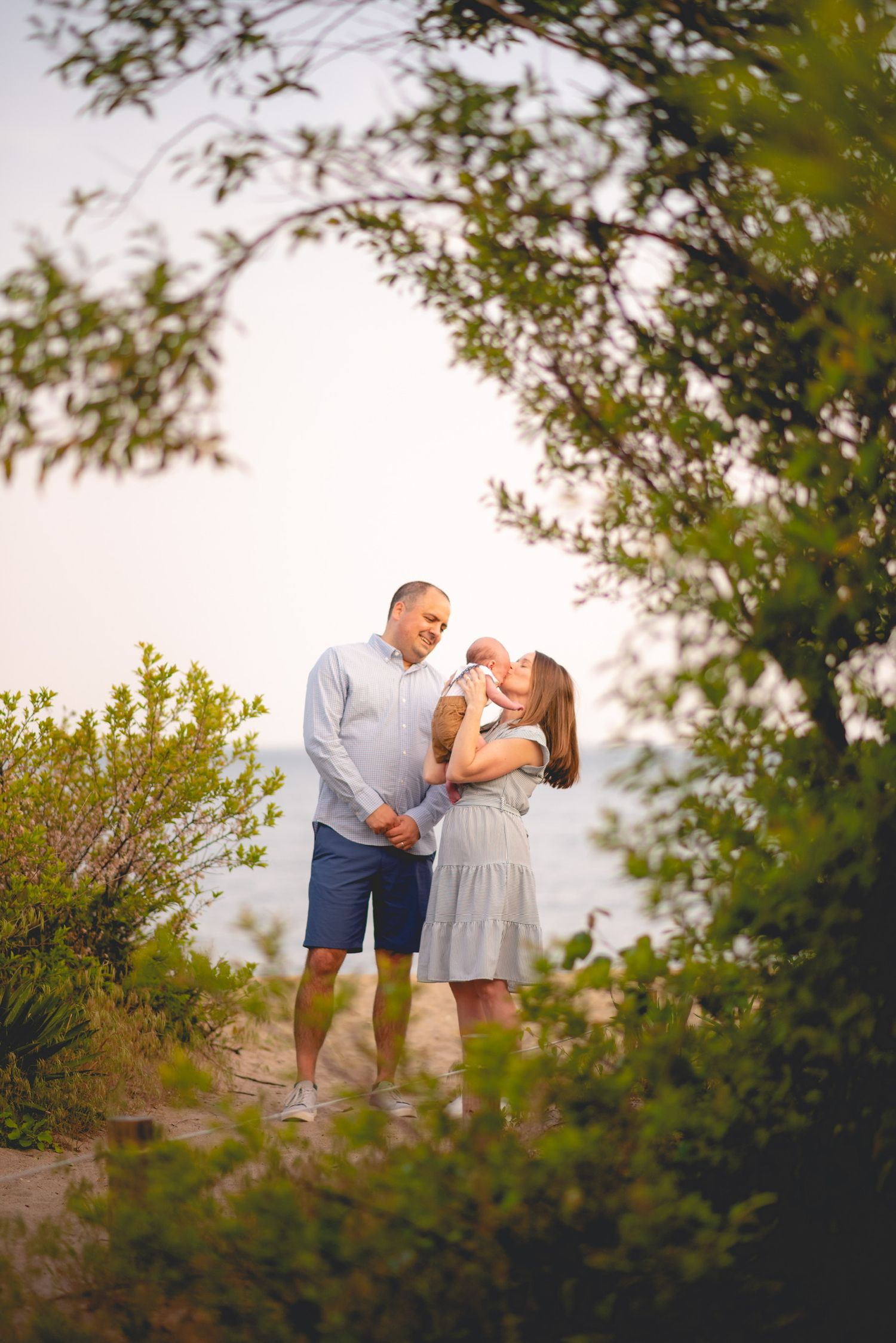 Tender family moments captured among green foliage during sunset.
