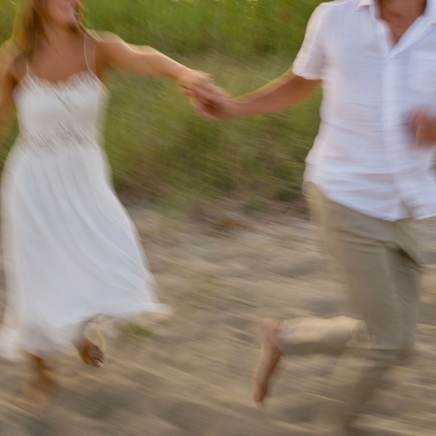 Motion-blurred figures in white clothing dancing on a beach.